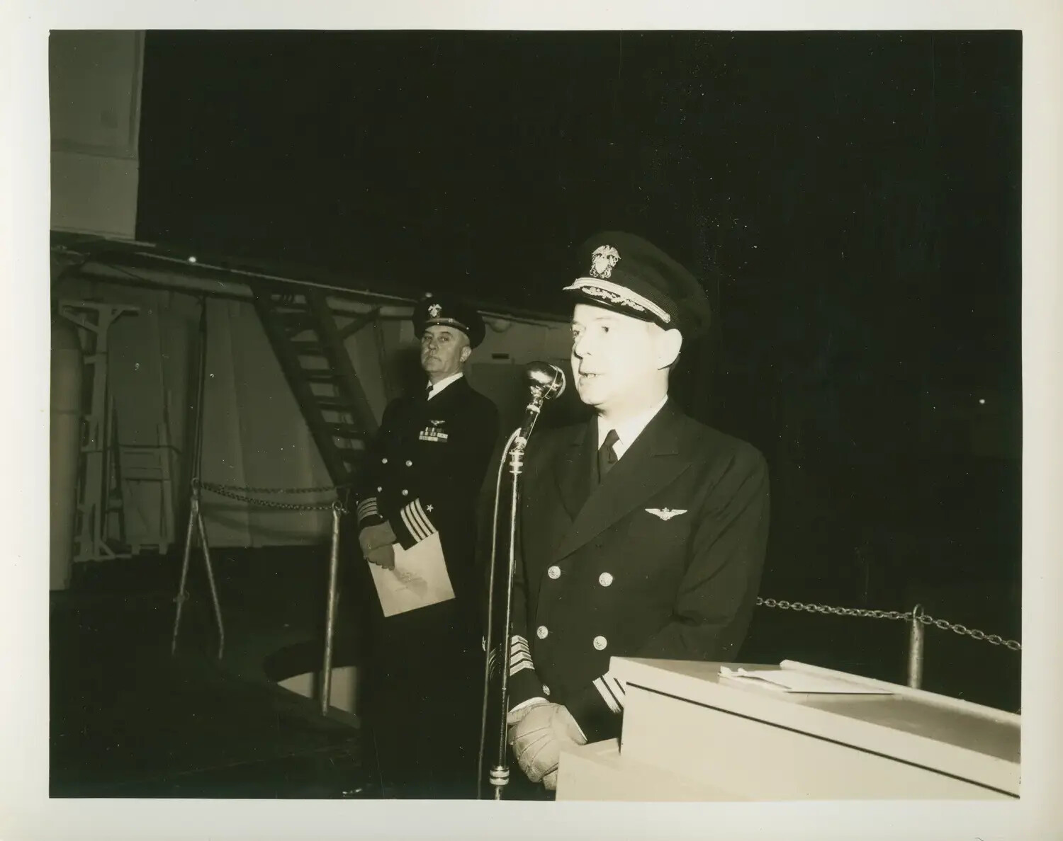 Shipboard Ceremony Aboard USS Petrof Bay (CVE-80), U.S. Navy Officer Addressing Assembly