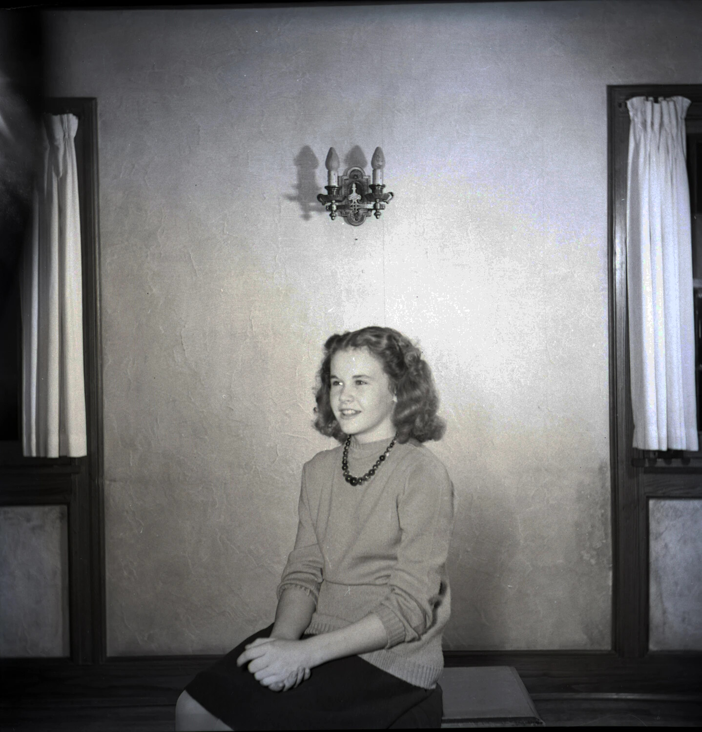 Domestic Portrait of Young Woman Seated Between Curtained Windows
