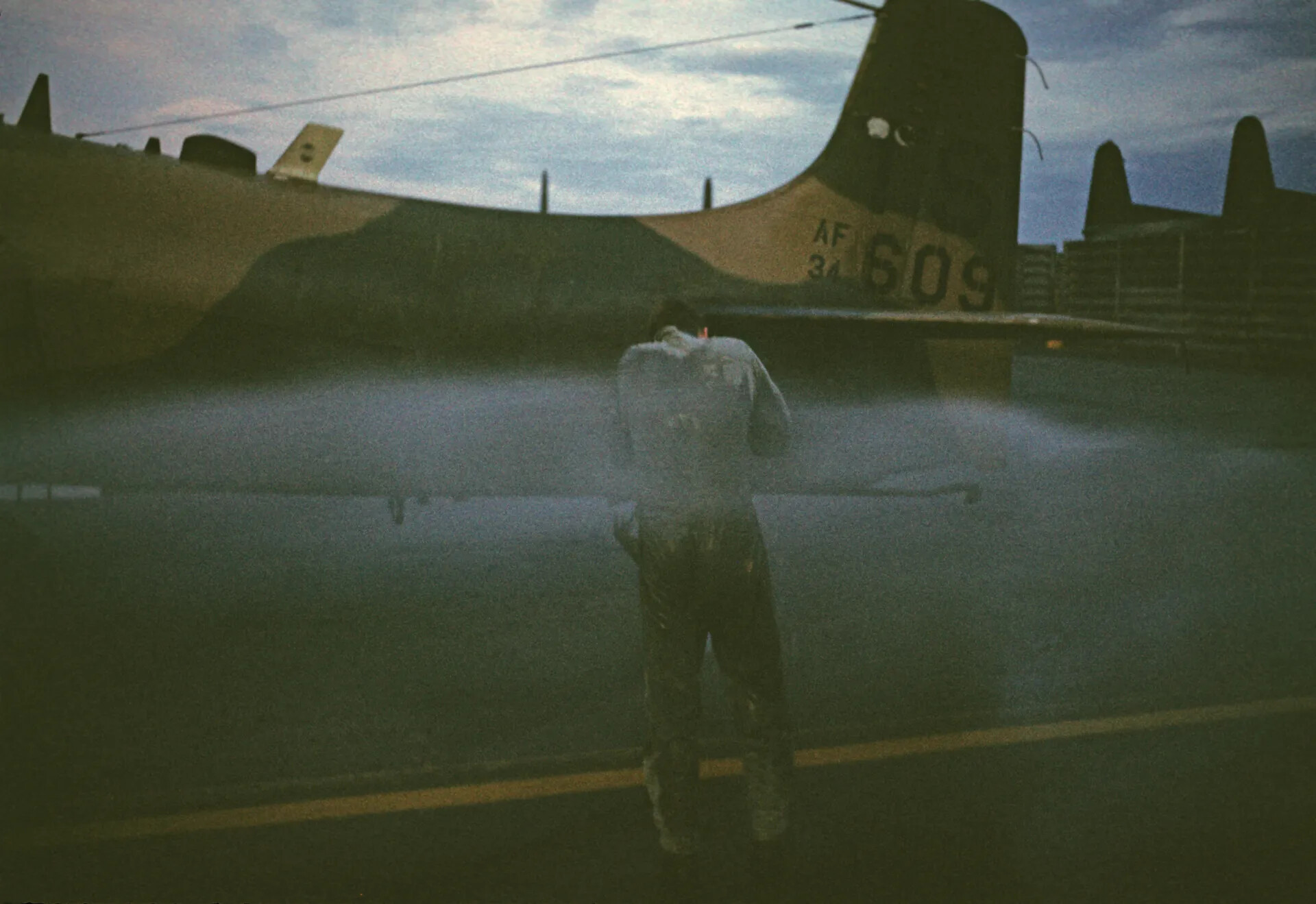 Airman Standing Before Aircraft Tail 'AF 34-609' in Low Light, Vietnam War Era