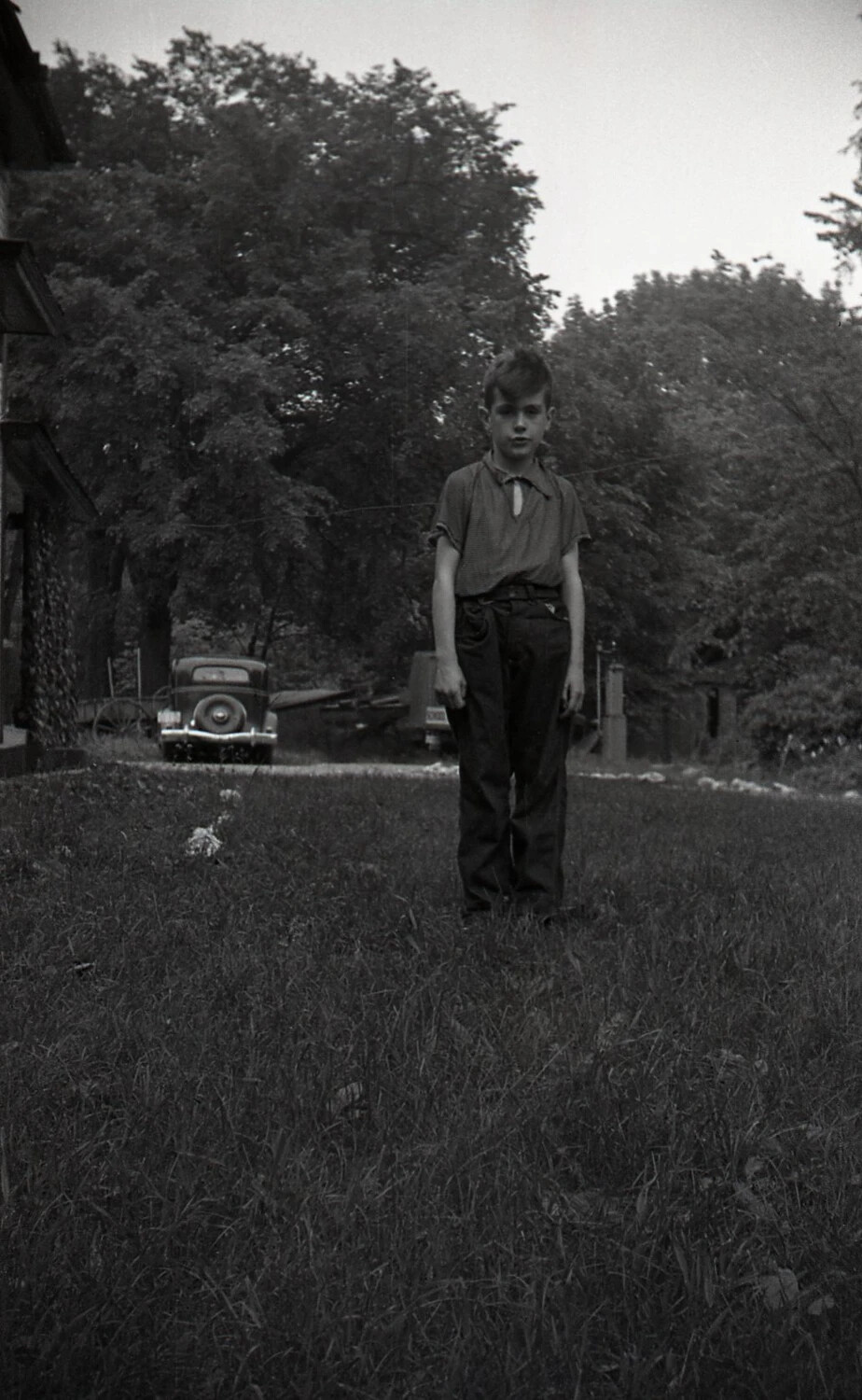 Boy Standing in Field Near Farmstead, Mid-20th Century
