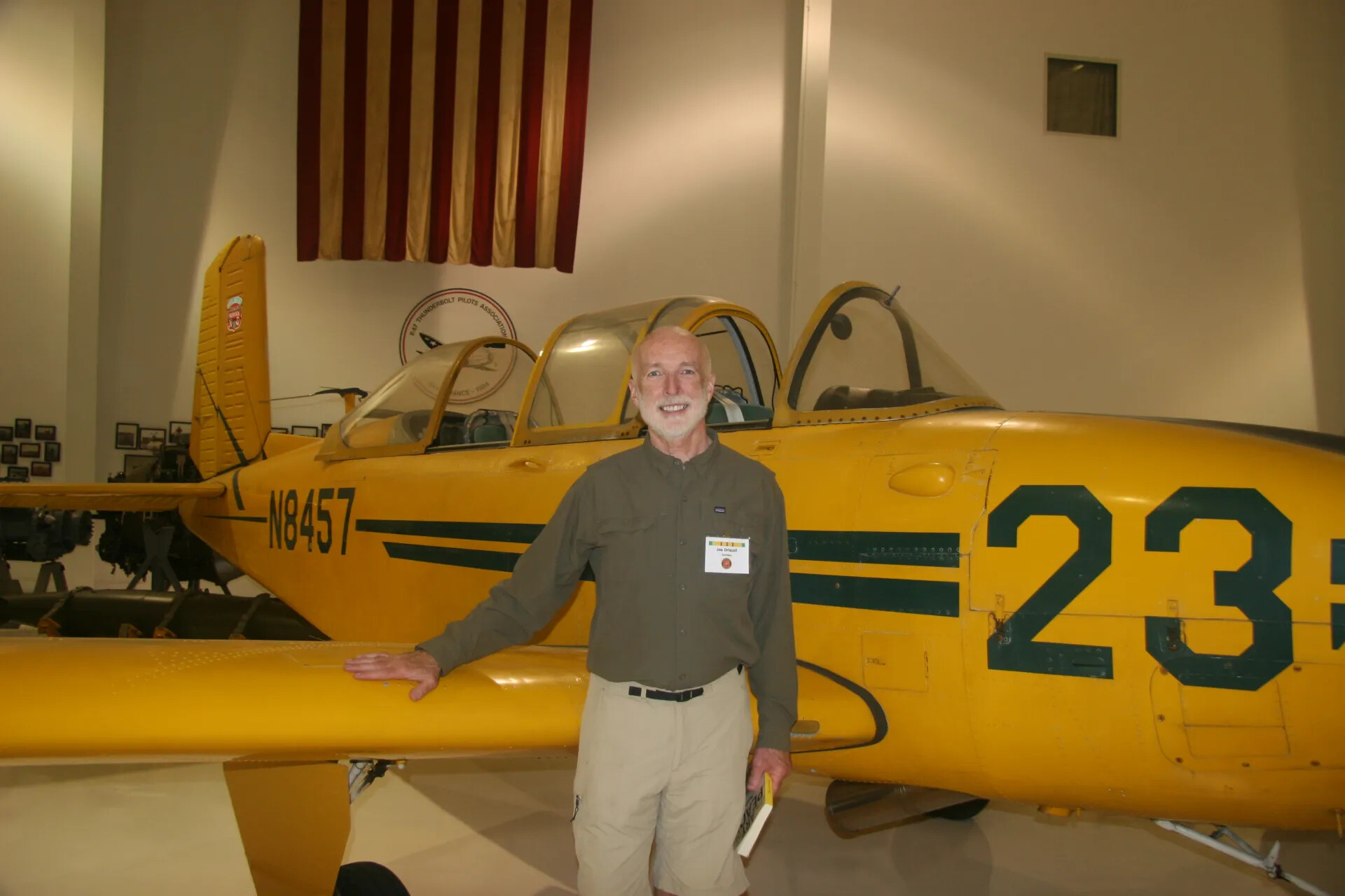 Reunion Attendee 'Joe Driscoll' Beside Restored Yellow Military Trainer Aircraft, Museum Display