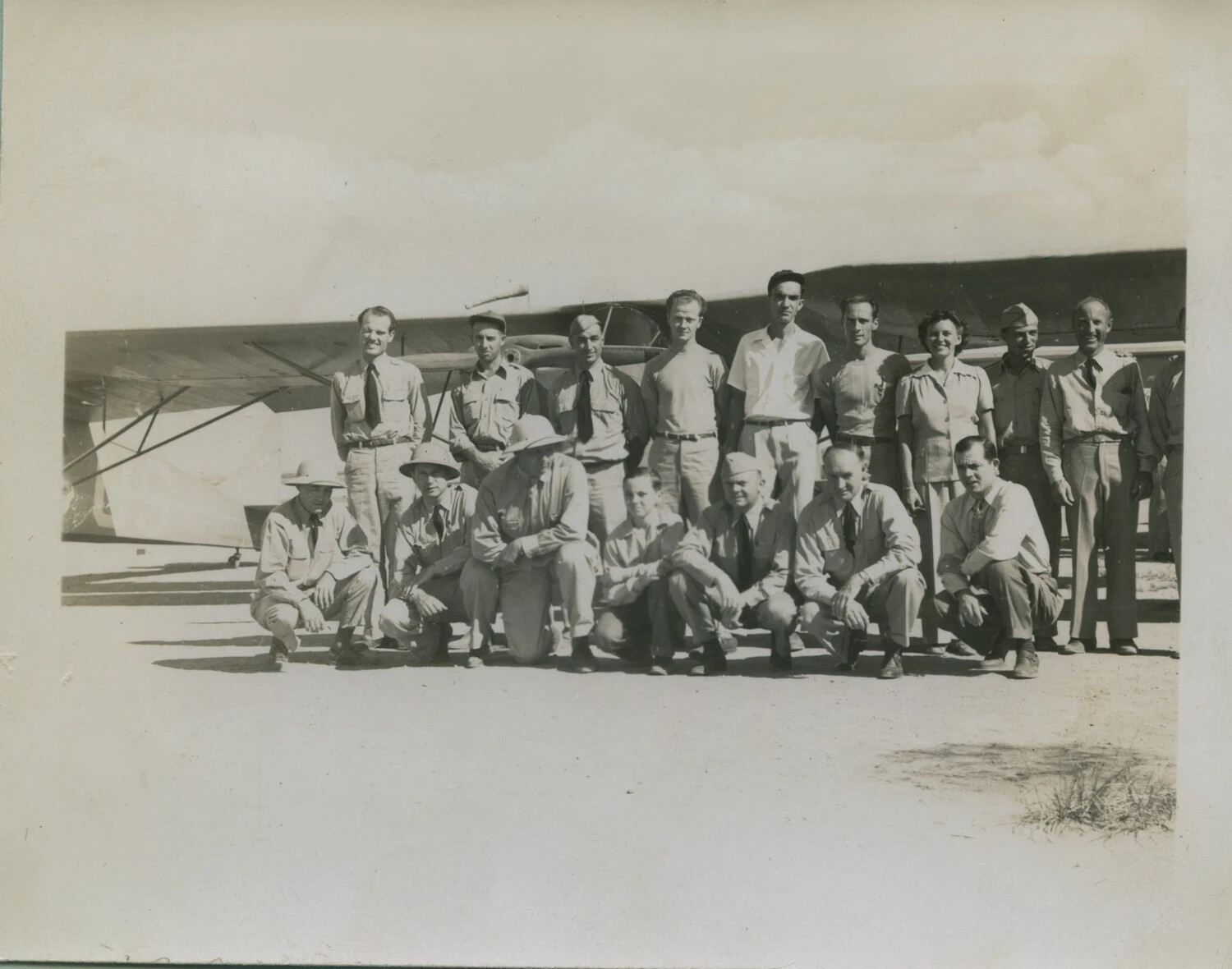 Group Portrait of Mixed Military and Civilian Personnel Before High-Wing Aircraft - McAleer Collection