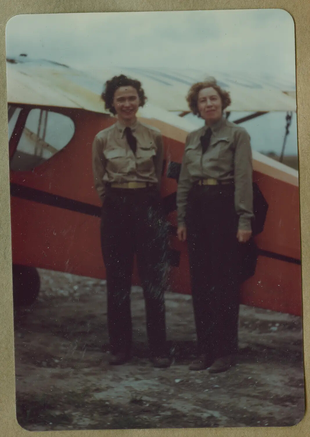 Two Women in Khaki Uniforms Beside a Light Training Aircraft