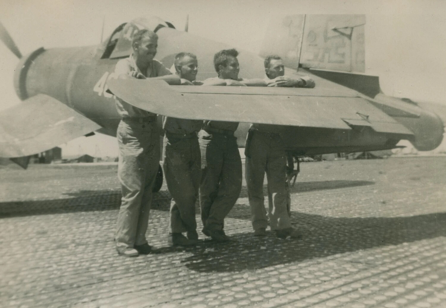 Four Servicemen Posing Beneath Folded Wing of Carrier Fighter Aircraft, WWII
