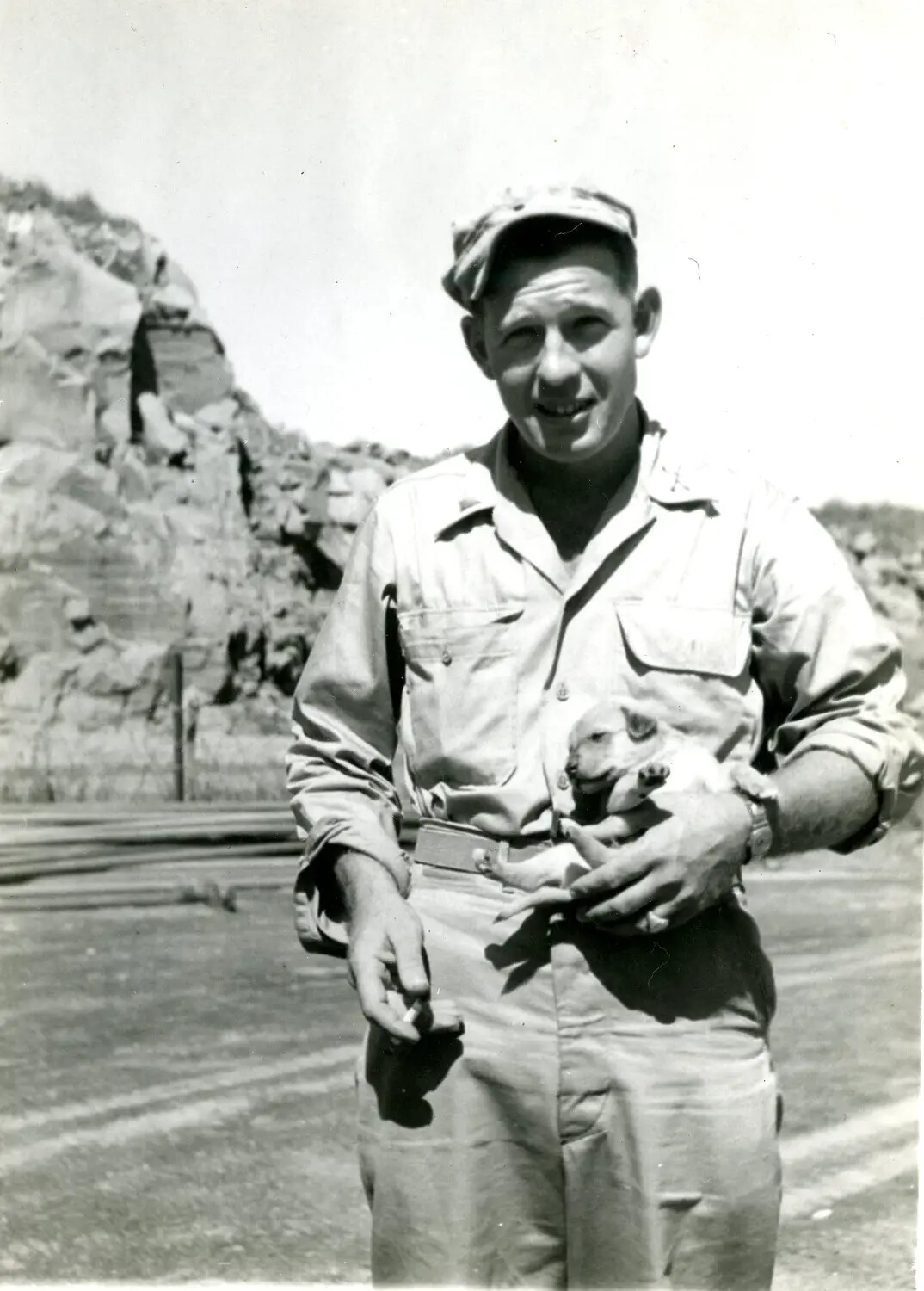 U.S. Marine Holding a Puppy Amid Iwo Jima's Volcanic Terrain, 5th Marine Division