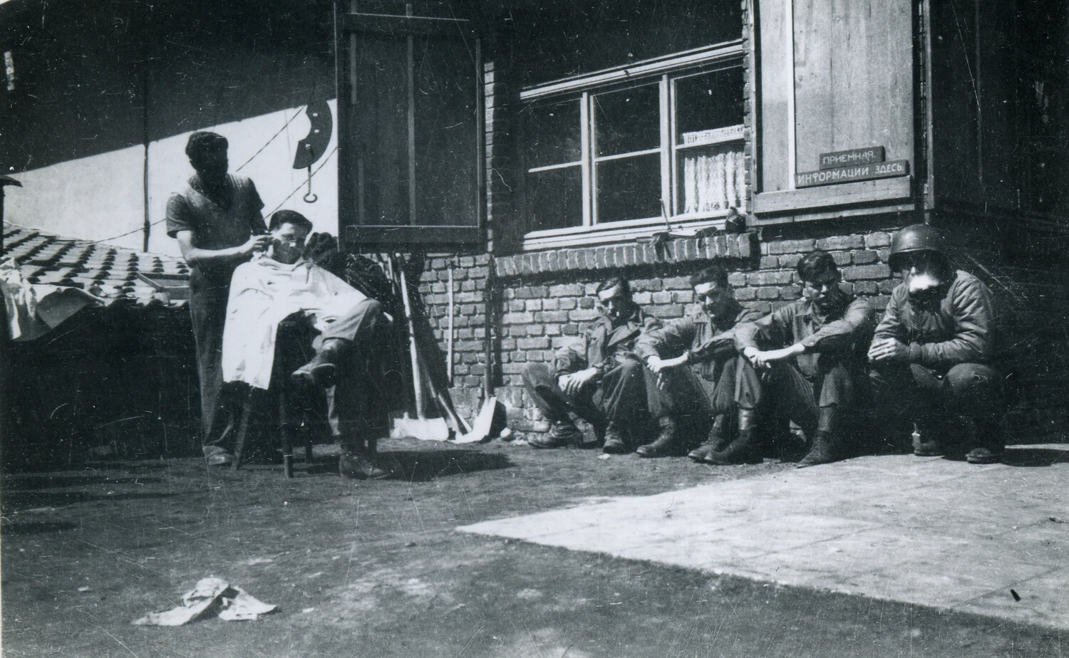 American Soldiers Await Haircuts Outside a Building with Russian-Language Signage, Postwar Occupation Zone