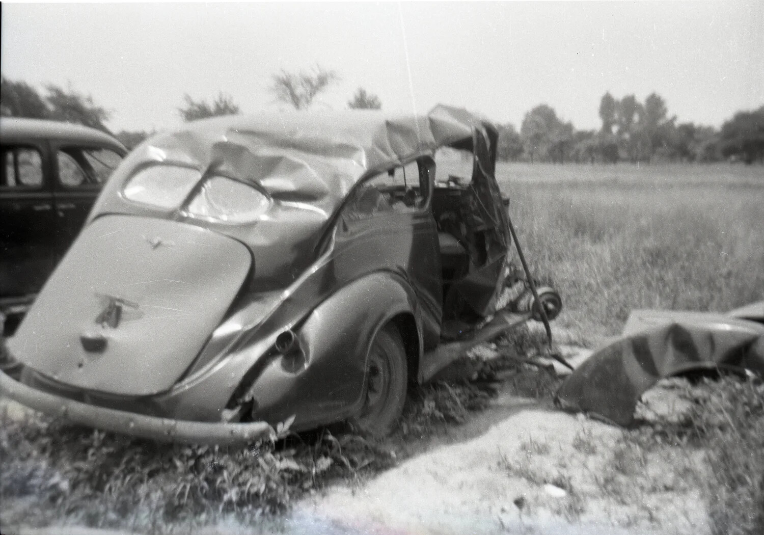 Wrecked 1930s Coupe in Rural Field, Front View with Hood Ornament Detail