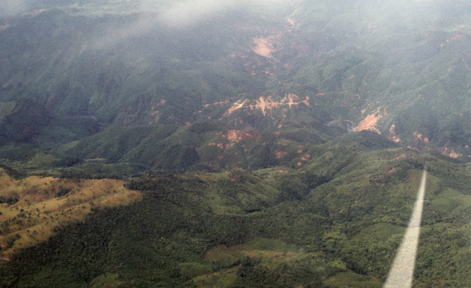 Aerial View of Bomb-Scarred Mountain Ridge with Aircraft Wing