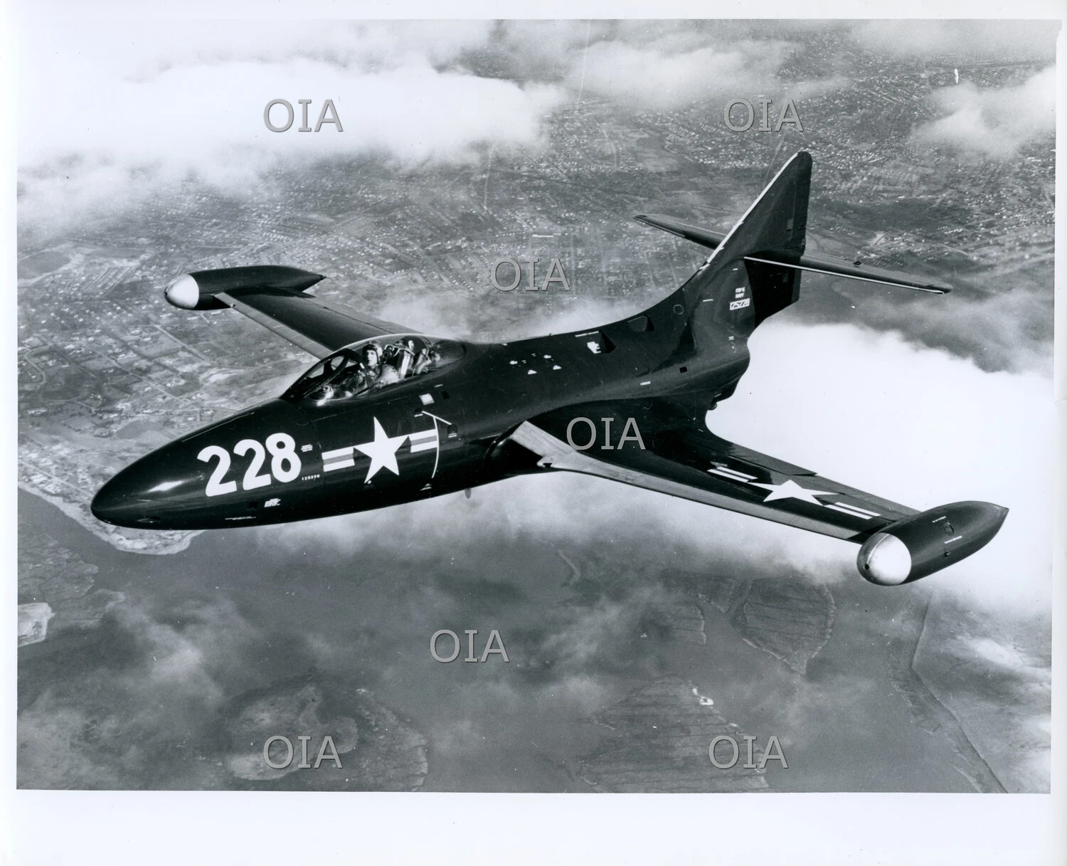 U.S. Navy Jet Aircraft '228' in Flight Over Coastal City