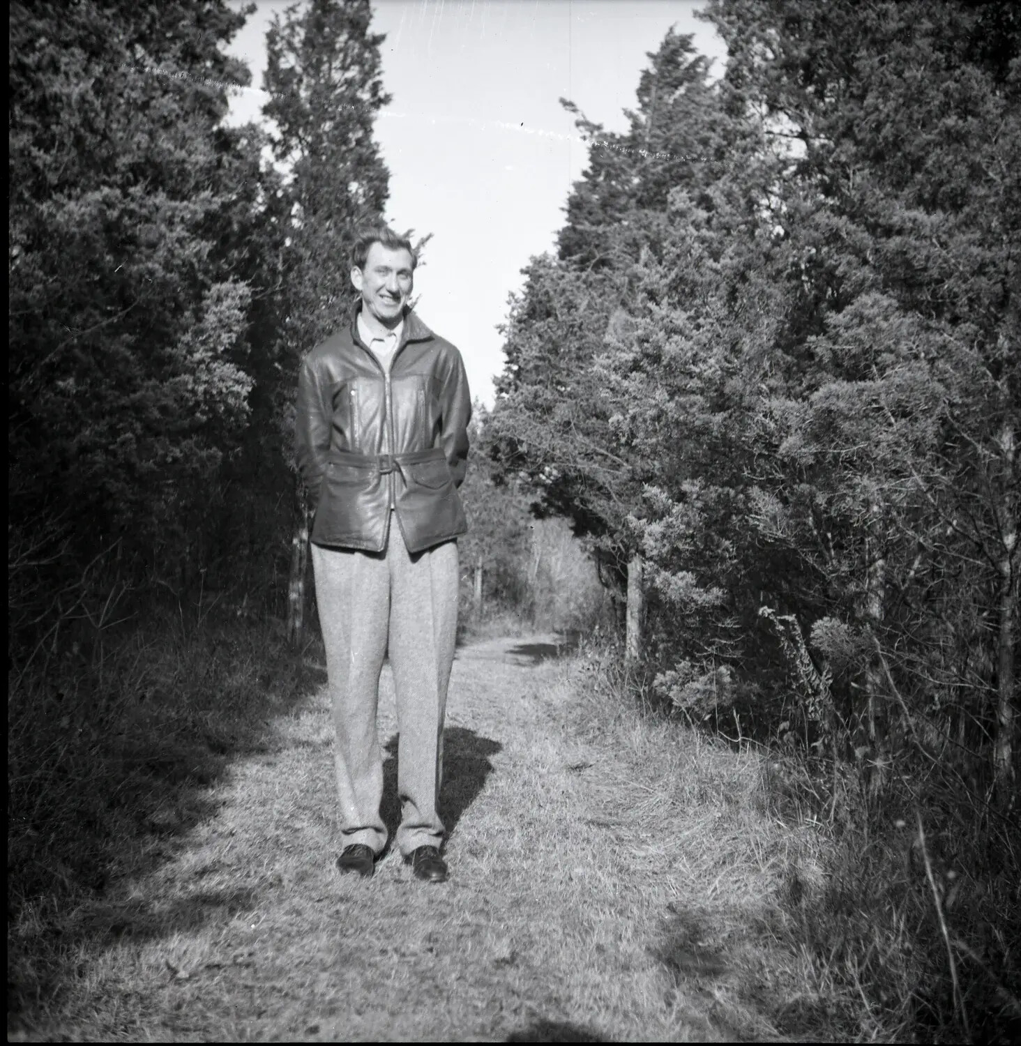 Young Man Standing on a Wooded Path in a Belted Leather Jacket