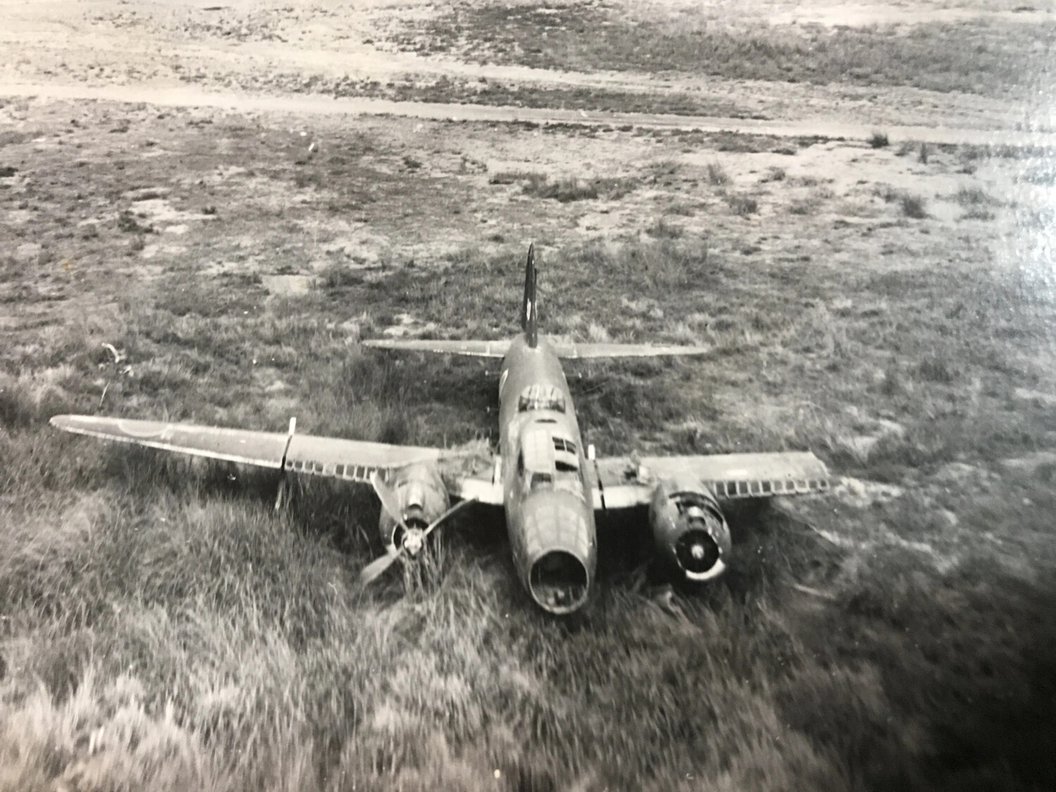 Wrecked Japanese Twin-Engine Aircraft in Field Beside Airstrip