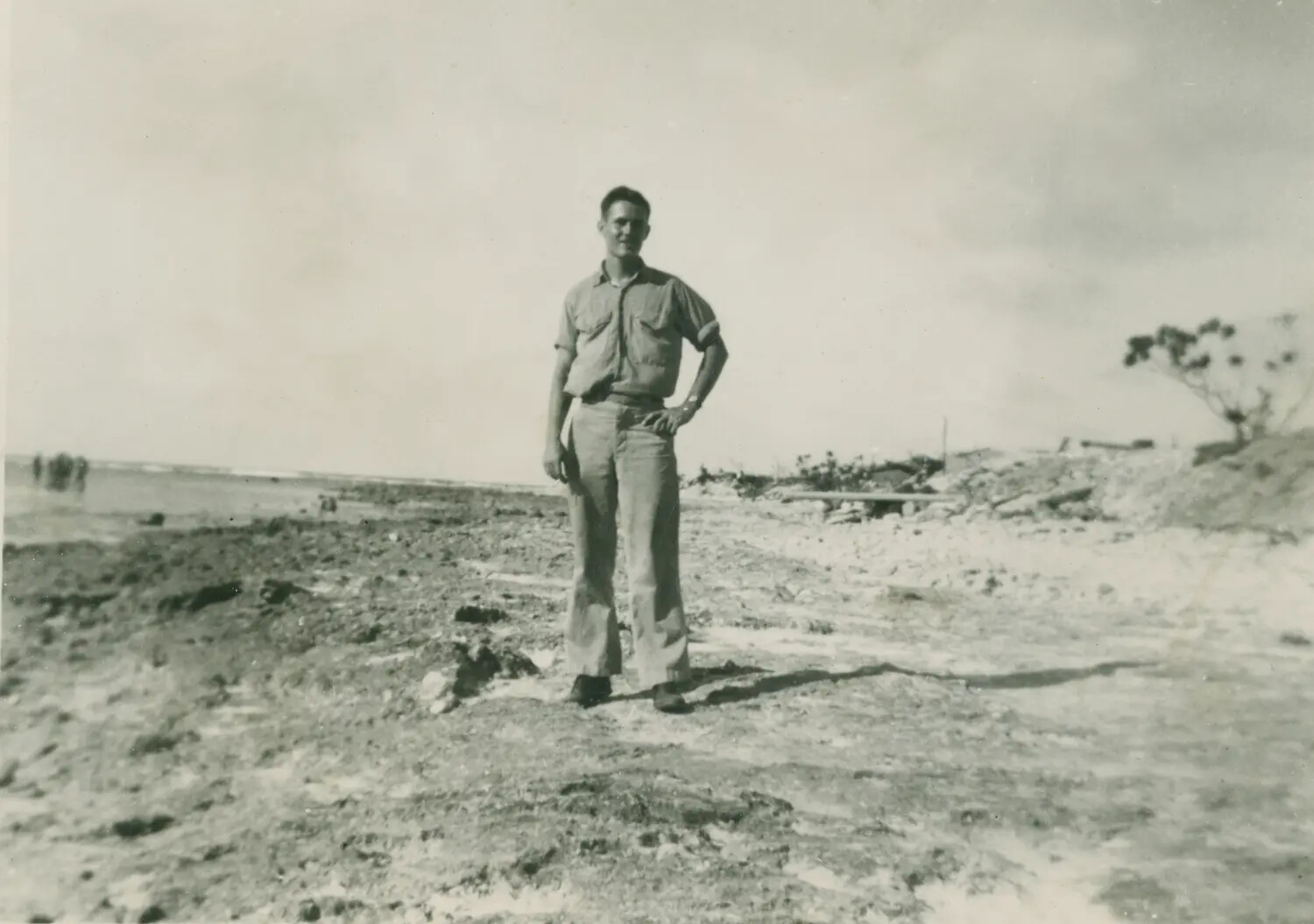 Serviceman Standing on Debris-Strewn Pacific Island Beach, WWII Era (McAleer Collection)