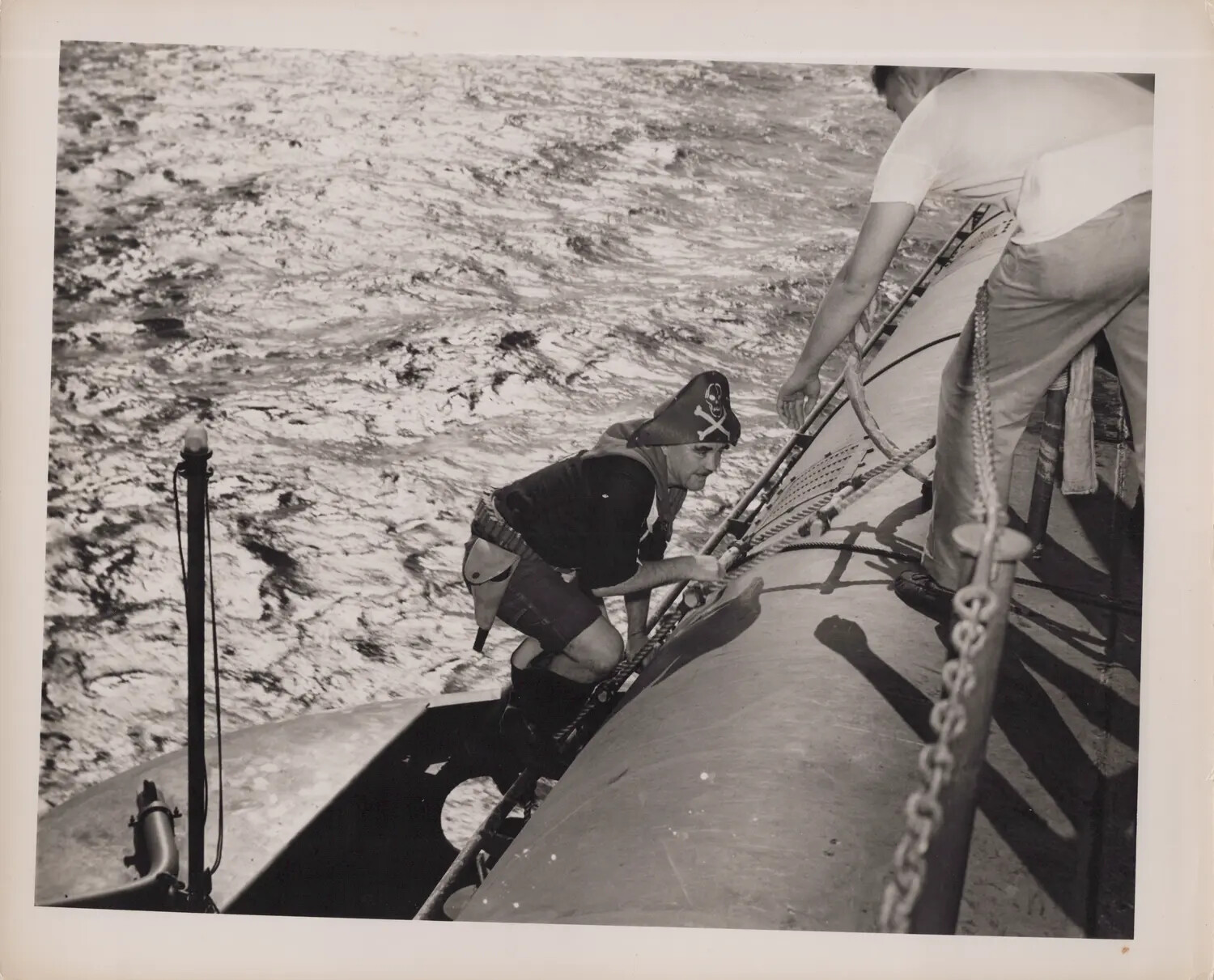 Sailor in Pirate Costume Climbing Submarine Deck During Shipboard Ceremony
