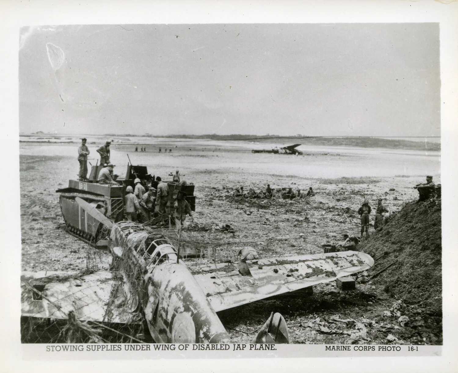 "Stowing Supplies Under Wing of Disabled Jap Plane" - US Marine Corps Photo 16-1, Okinawa, 1945