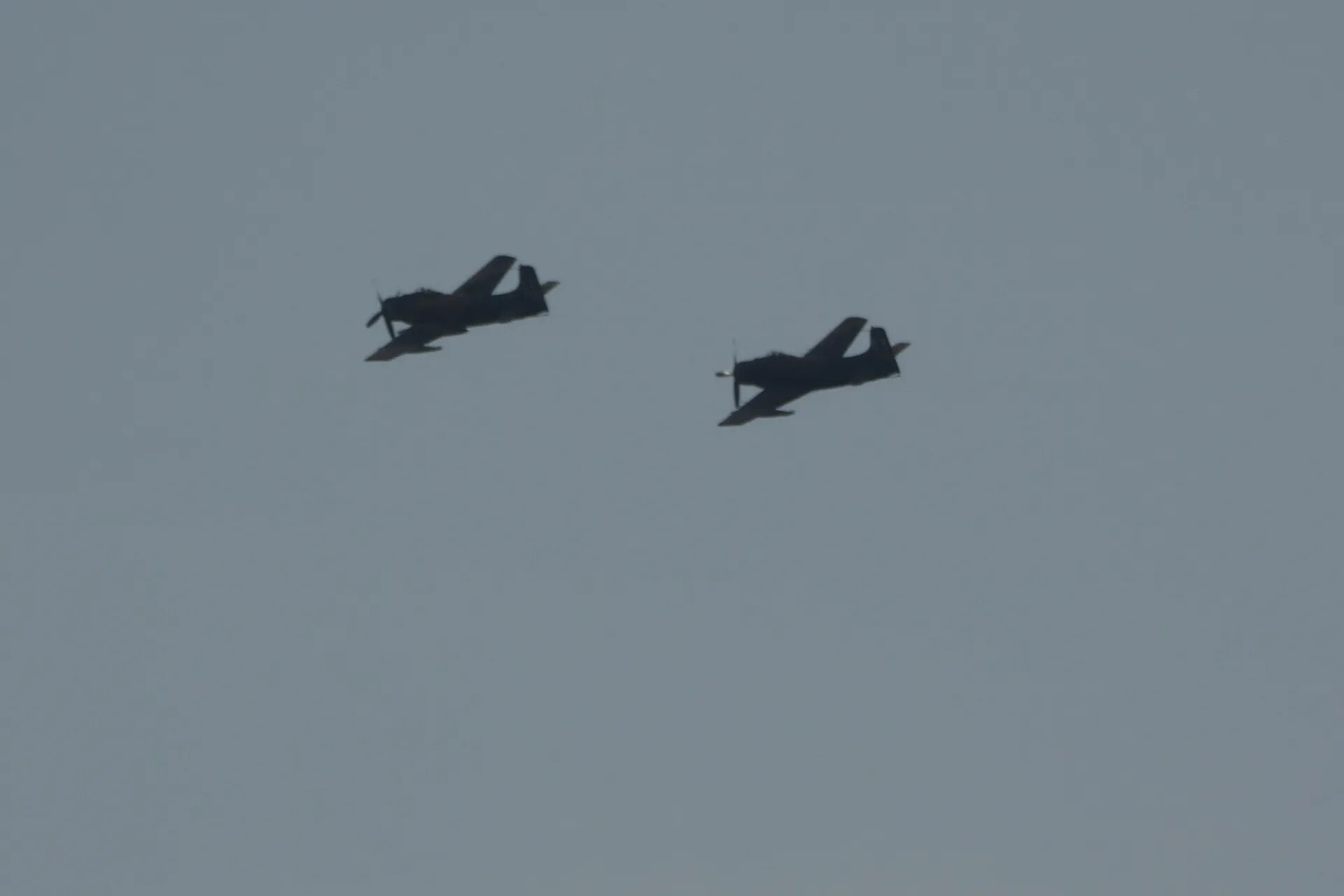Two A-1 Skyraiders Banking in Formation Against Hazy Sky
