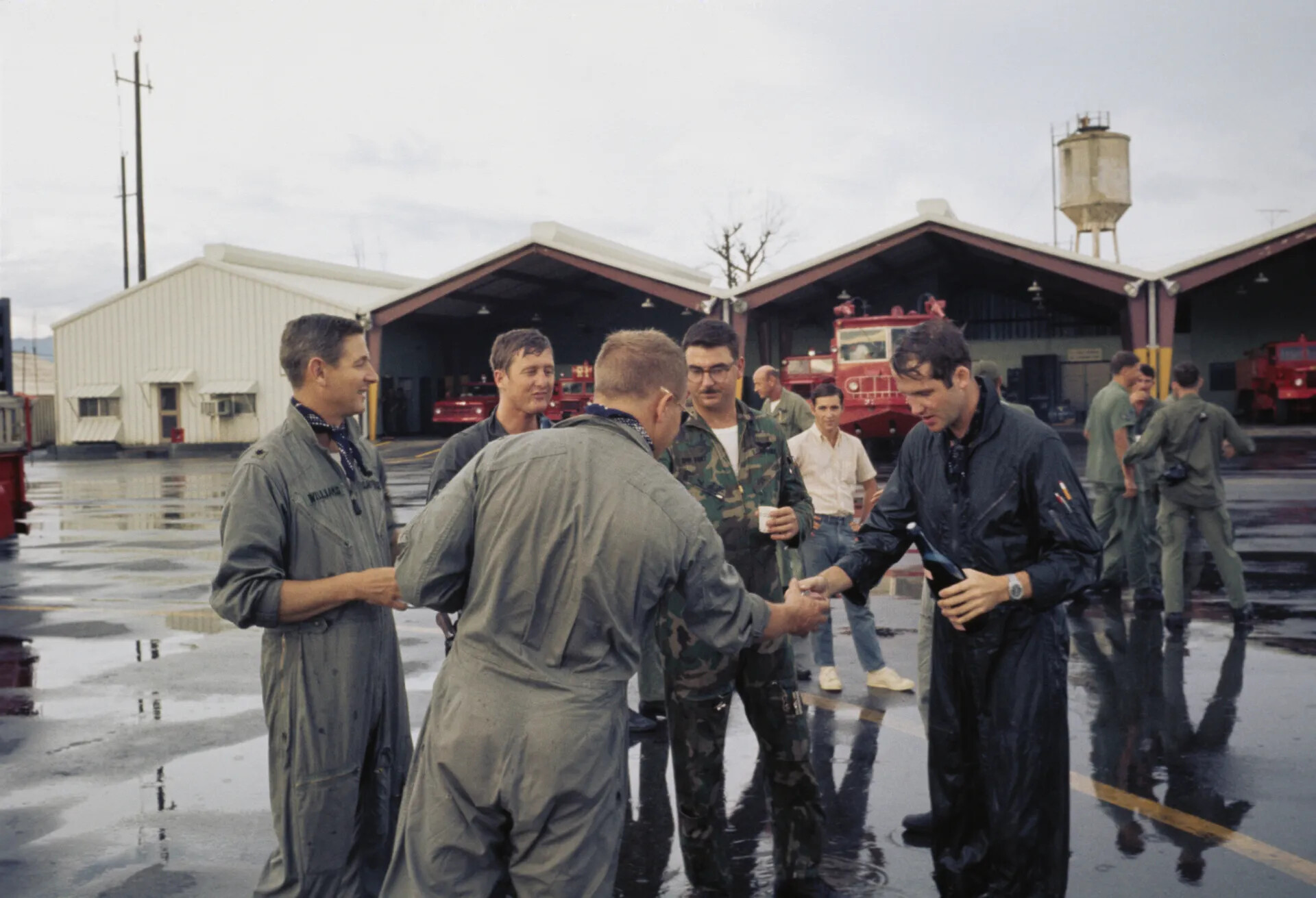 USAF Personnel Celebrating with Champagne After Wetting-Down Ceremony, Fire Station Backdrop, Vietnam War