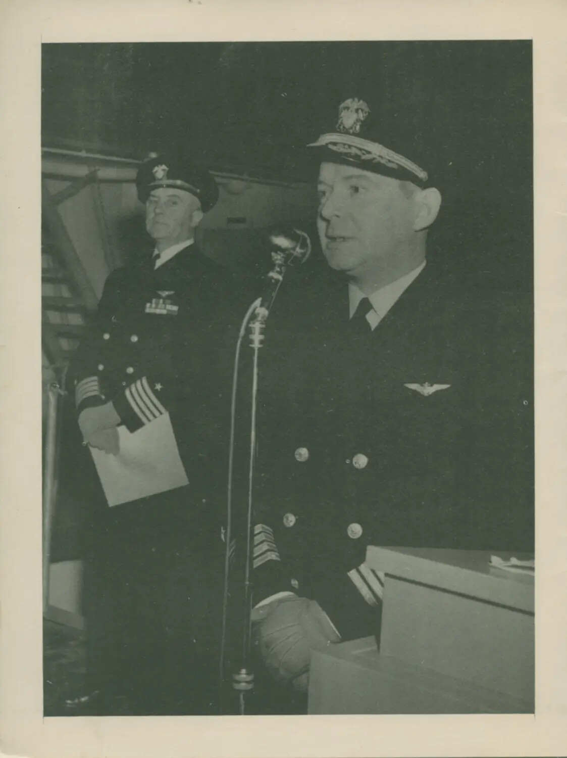 Naval Officer Addressing Ship's Company at Microphone Aboard USS Petrof Bay (CVE-80)