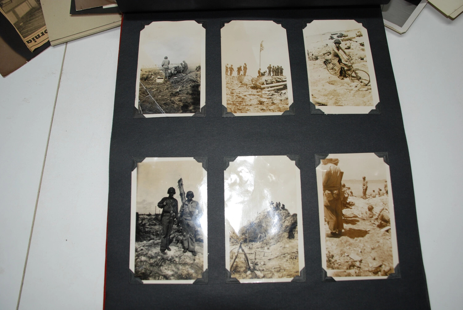Album Page of Six Combat Snapshots -- Flag Raising, Beach Bicycle, and Infantry with Bazooka, Jack T. Kelley Album
