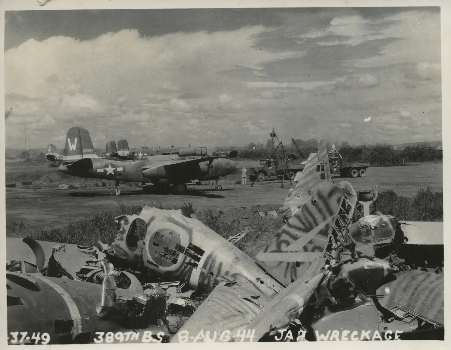 B-25 Mitchell of the 389th Bombardment Squadron with Foreground Japanese Aircraft Wreckage — 8 August 1944