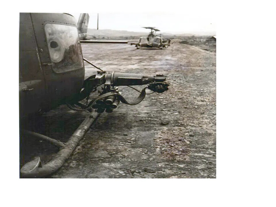 Helicopter Gunship Weapons Pod and Second Helicopter on Unpaved Airfield