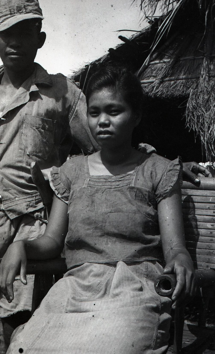Portrait of Filipina Woman and Man in Fatigue Uniform Outside Nipa Hut, Luzon, Philippines, WWII Era