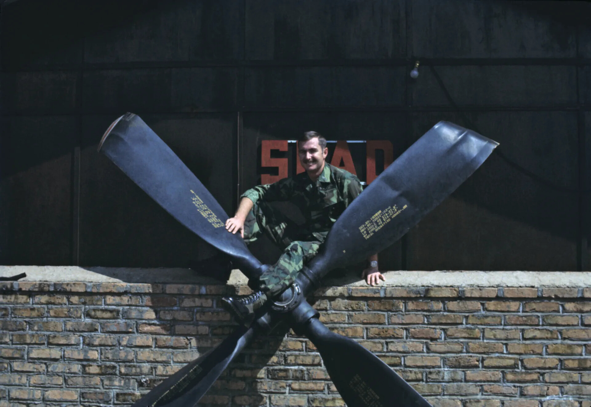 USAF Airman Seated on Crossed Propeller Blade Display, Vietnam-Era Squadron Building