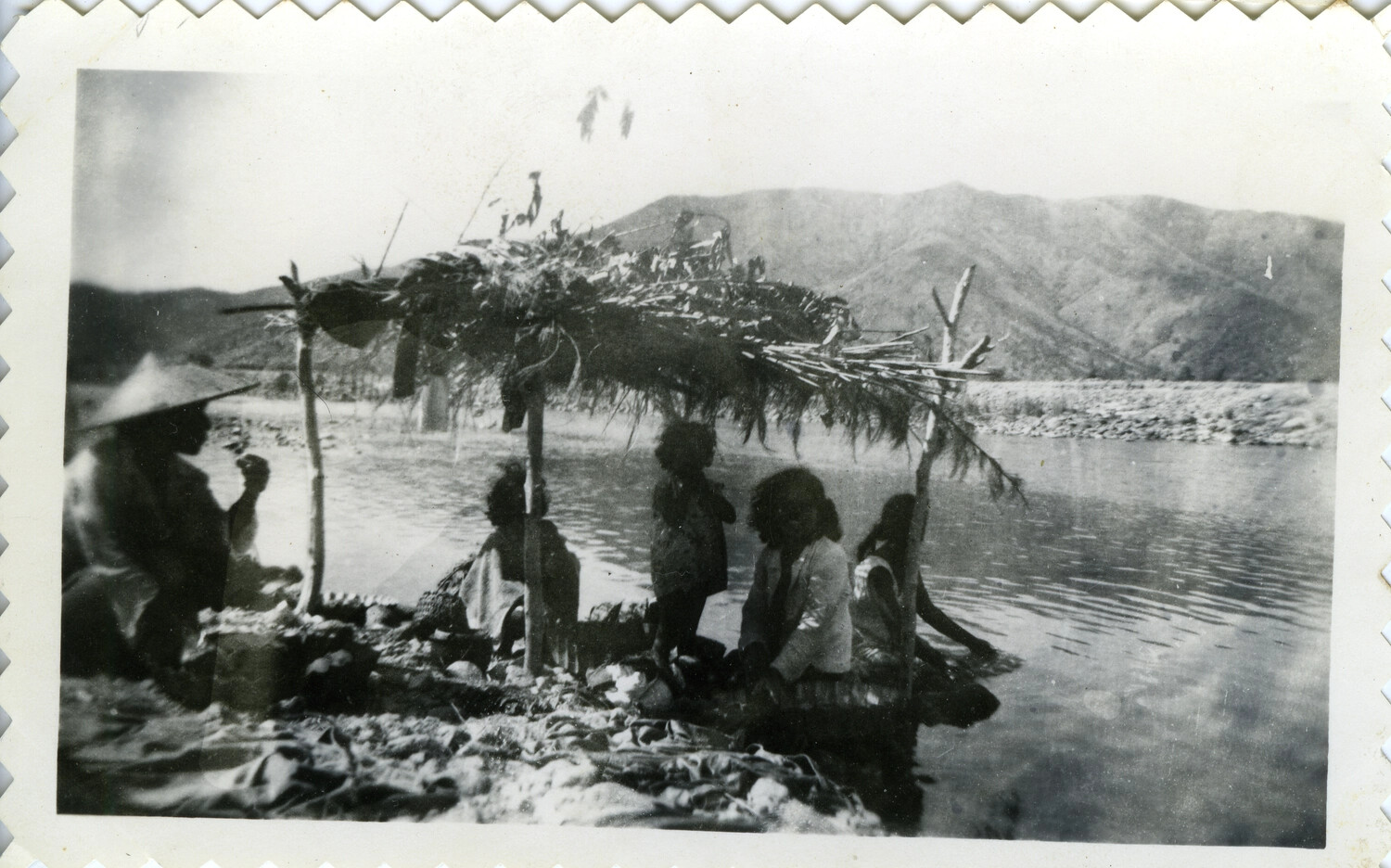 Displaced Civilians Sheltering Beneath a Makeshift Lean-To by a River, Okinawa, 1945