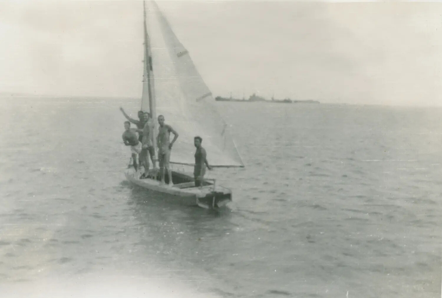 Sailors Sailing a Small Boat During Off-Duty Recreation, with Warship in Background