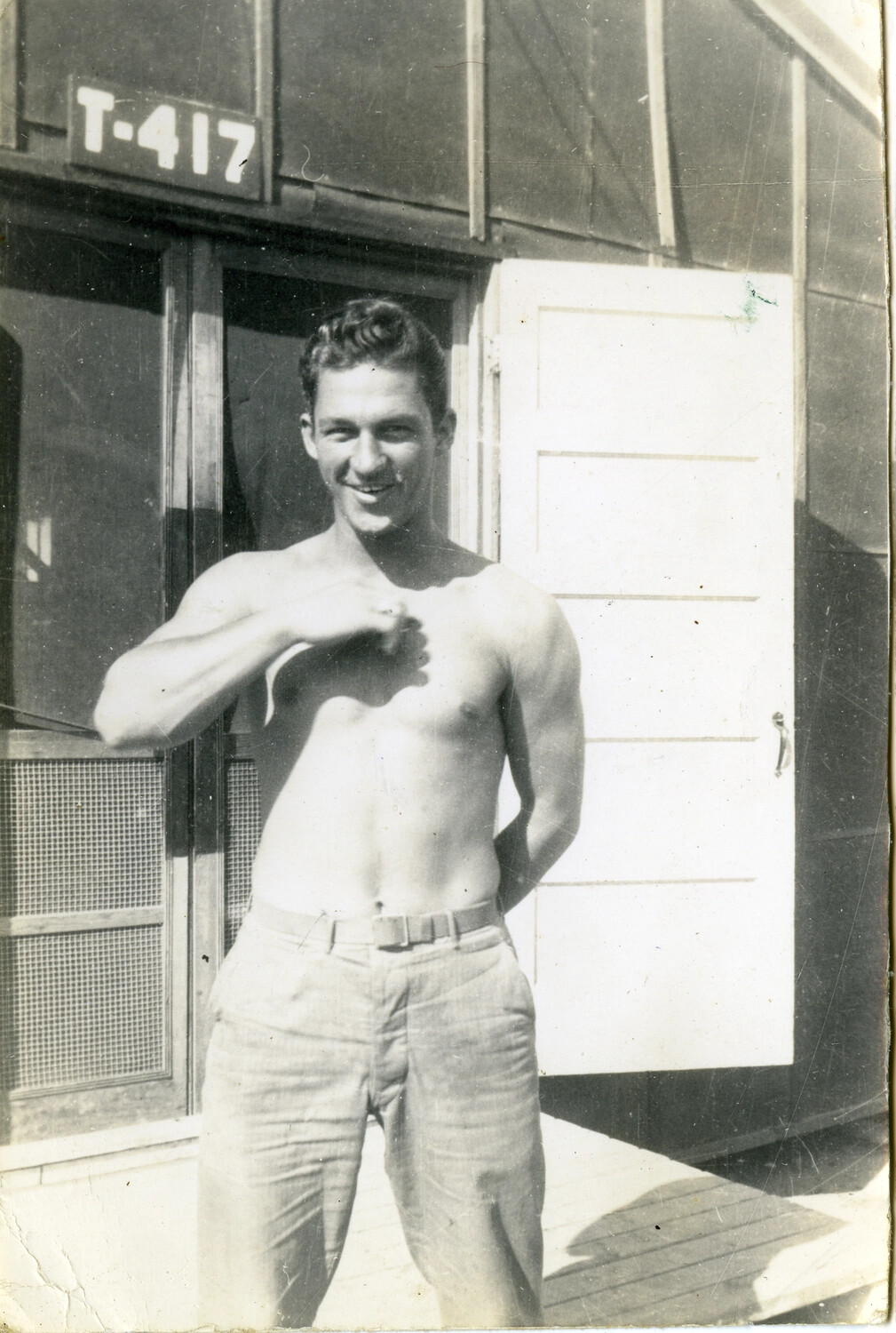 Shirtless Serviceman Posing in Front of Barracks Hut 'T-417', Pacific Theater, World War II Era