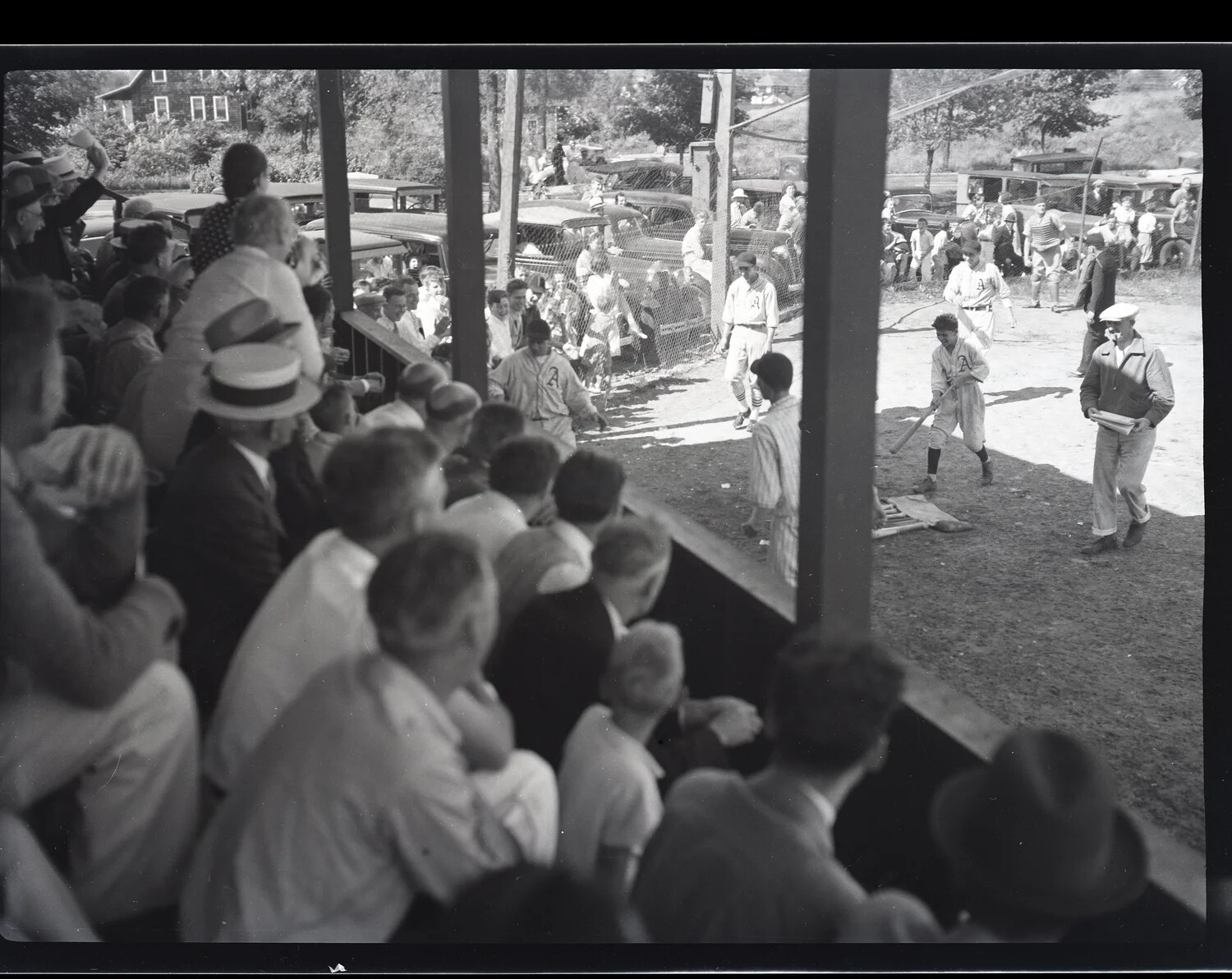 Small-Town Baseball Game with Grandstand Crowd and Period Automobiles
