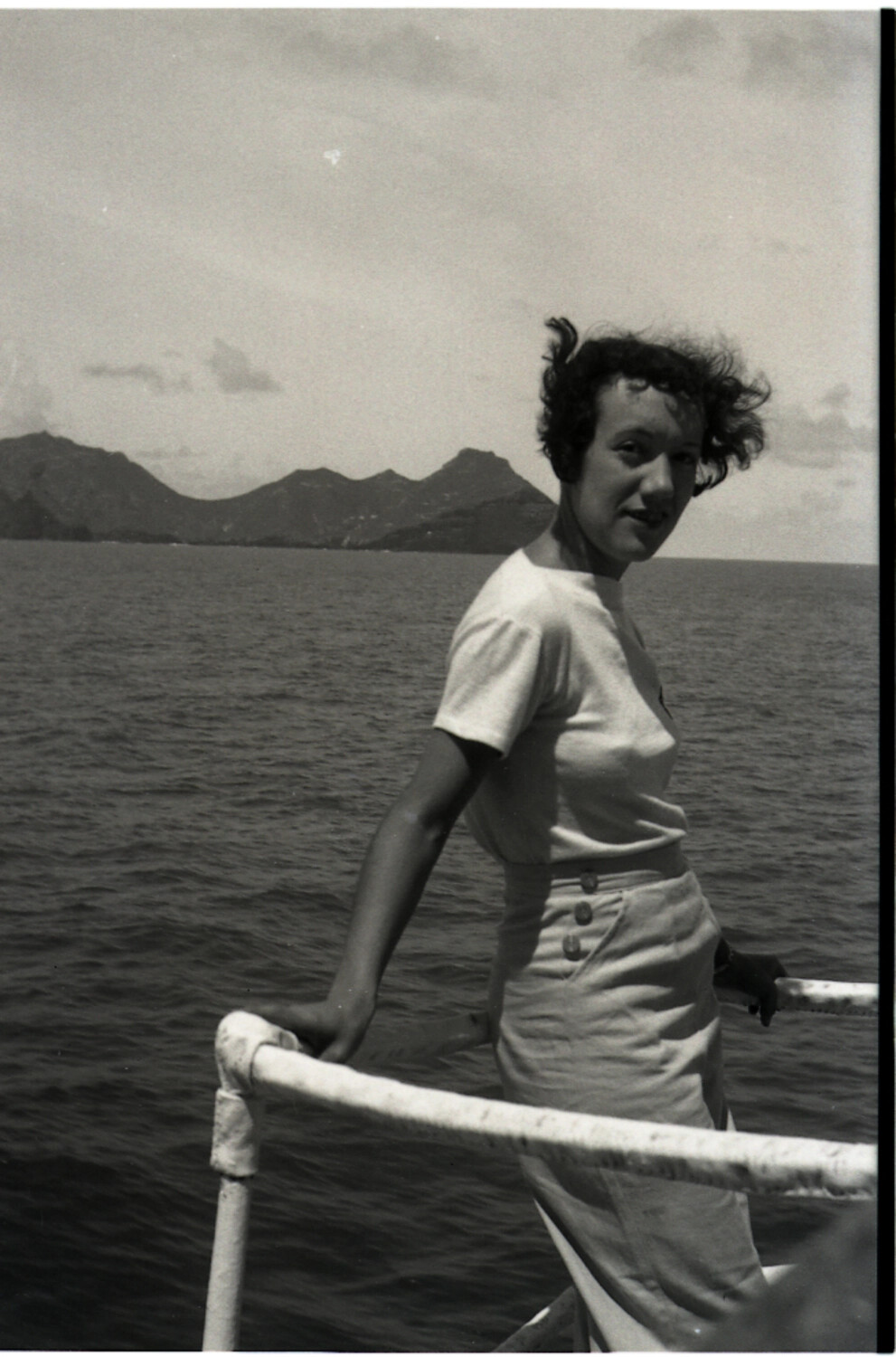 Young Woman at the Ship's Rail, Volcanic Coastline Beyond