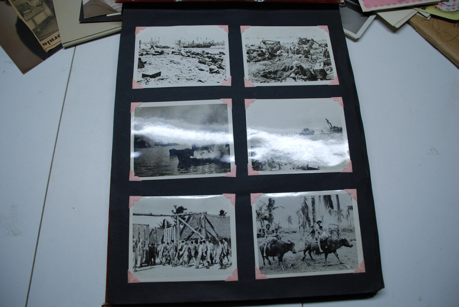 Album Page of Six Wartime Snapshots -- Beachhead Wreckage, Naval Bombardment, Troop Formation, and Water Buffalo, Jack T. Kelley Album