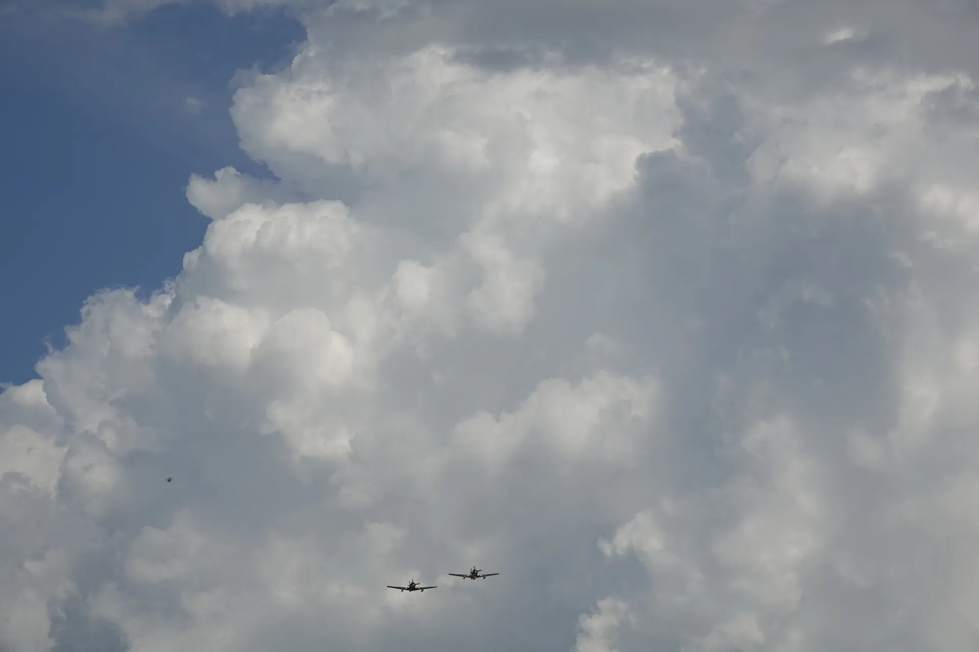 Formation Flypast of Two Warbirds Beneath Towering Cumulus Clouds