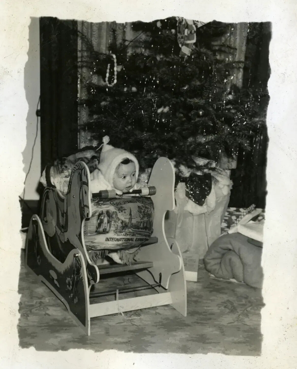 Infant in Decorative Wooden Sled Before a Christmas Tree, Family Album Photograph (1930s)