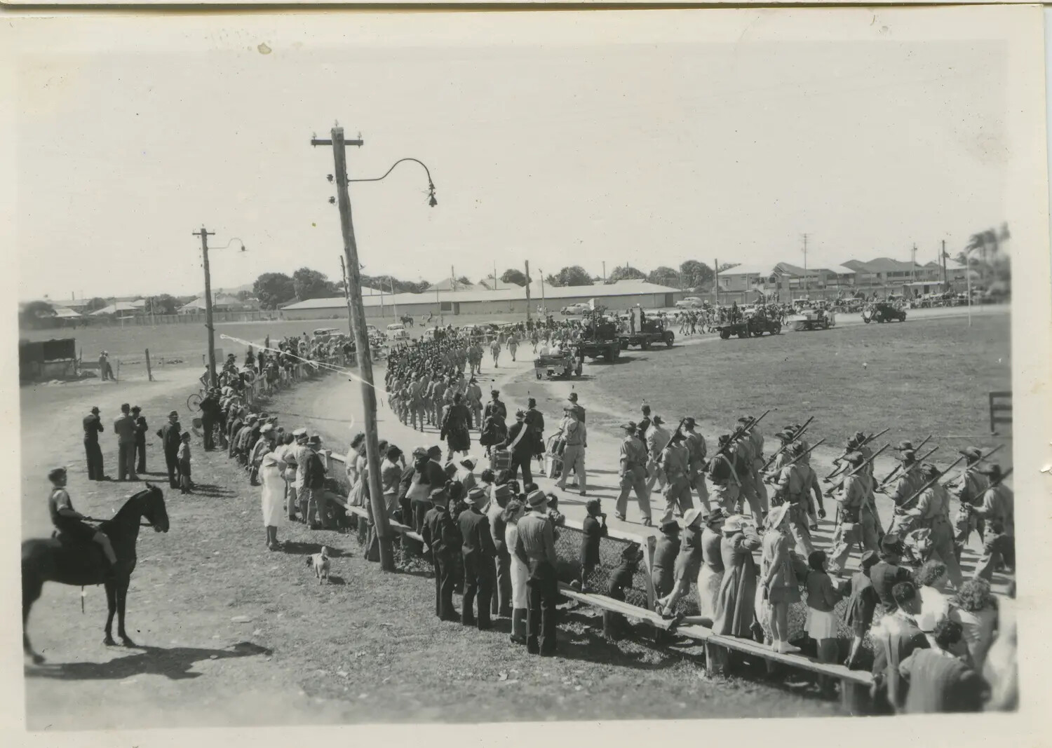 Military Parade Through Australian Town with Marching Troops and Civilian Spectators