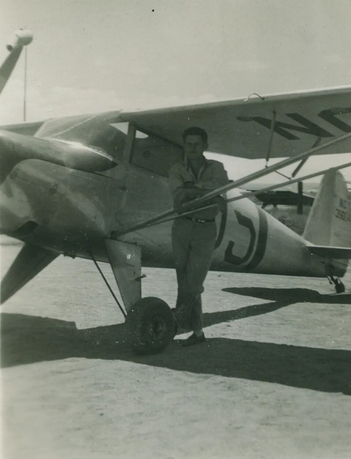 Man Posing Beside a Light High-Wing Training Aircraft with 'NC' Civil Registration