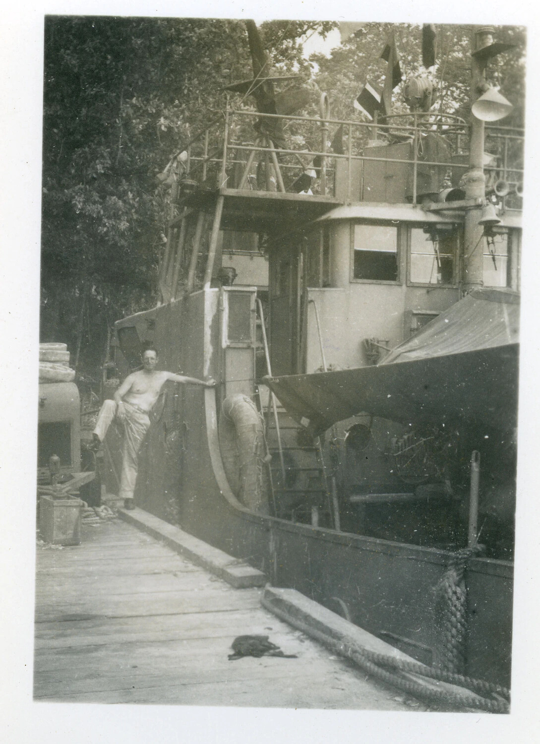 Sailor Aboard a Small Naval Auxiliary Vessel Moored at a Jungle Riverbank, Pacific Theater, WWII