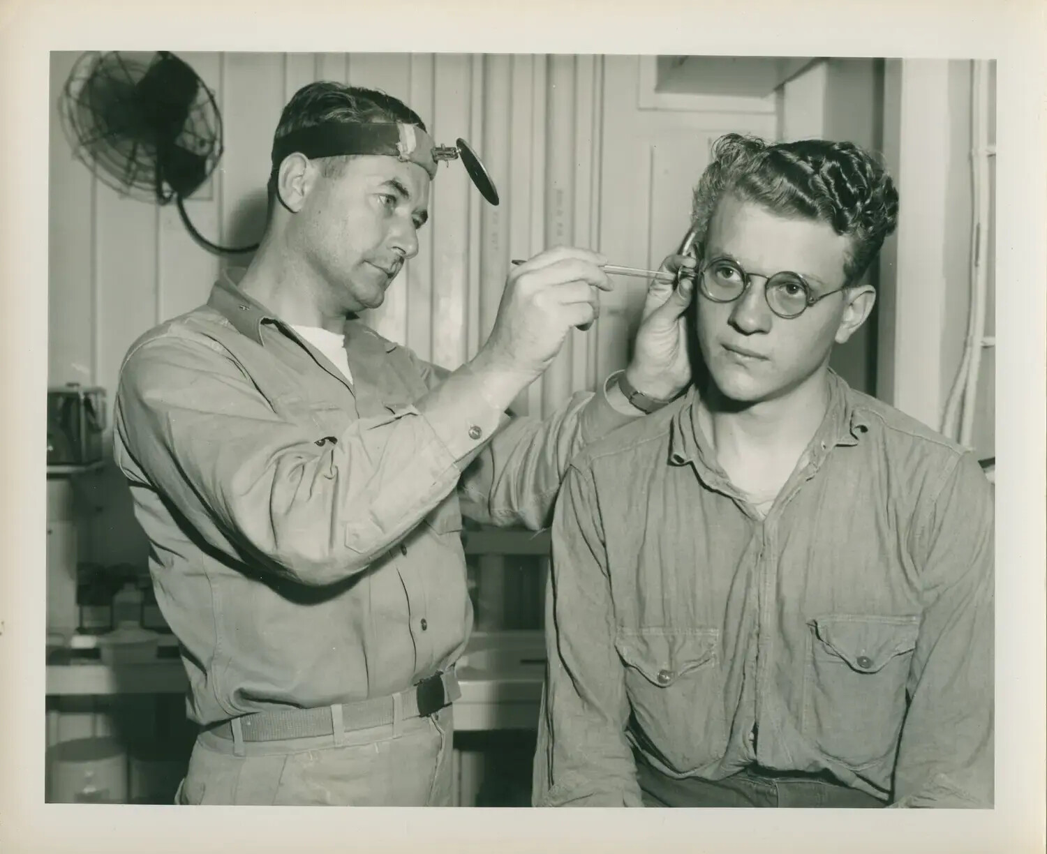 Navy Medical Officer Examining Sailor's Ear Aboard USS Petrof Bay (CVE-80), WWII