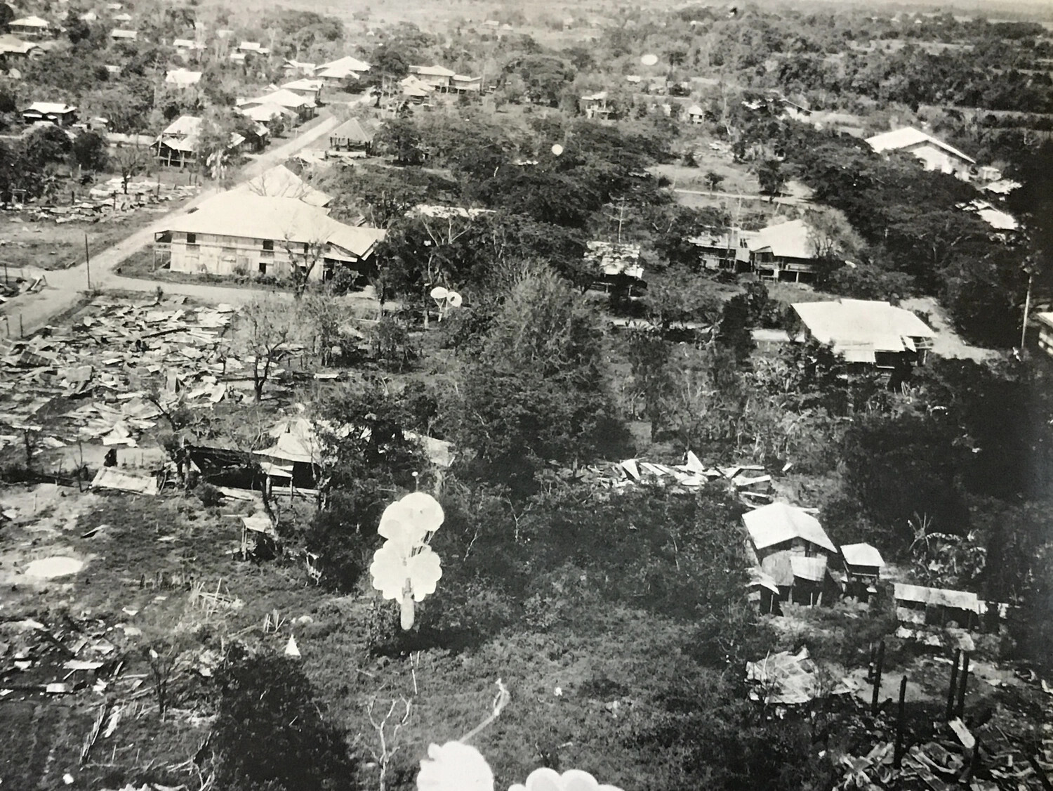 312th Bomb Group Strike Photograph — Parafrag Bomb Descending Over Damaged Luzon Town