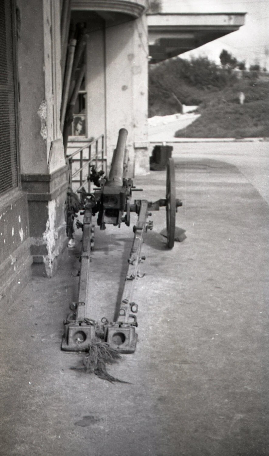 Abandoned Wheeled Field Gun Outside Damaged Building, Luzon, Philippines, 1945 (Profile View)