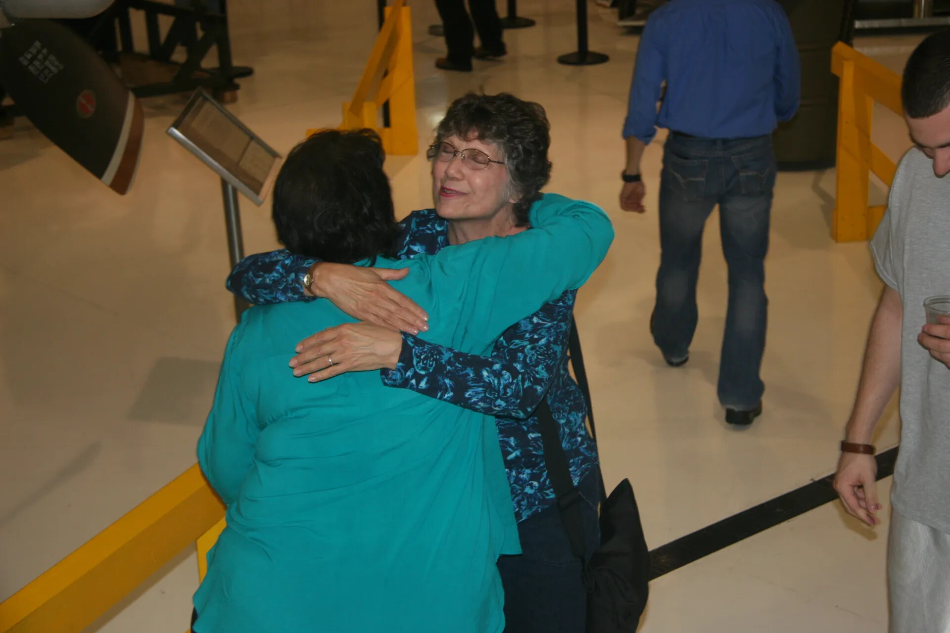 Emotional Embrace Between Two Women at Reunion Event, Museum Exhibit Hall