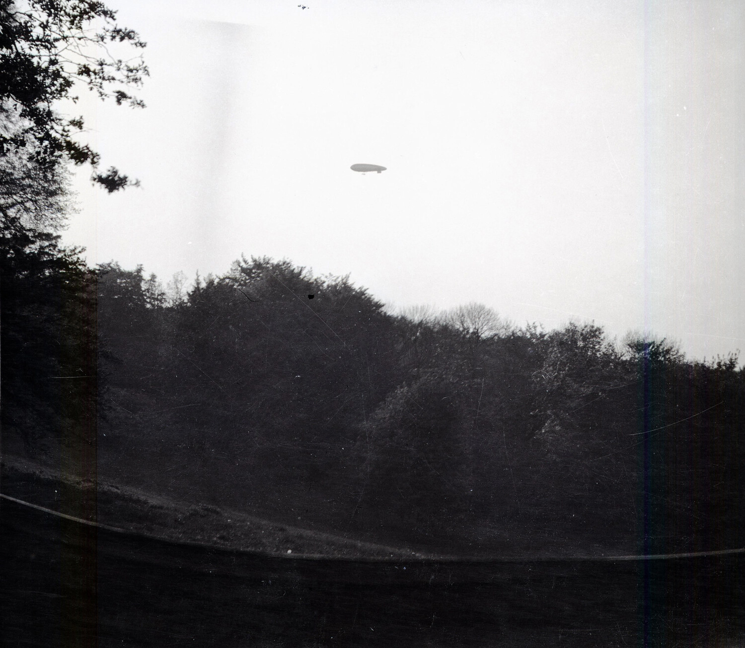 Distant Non-Rigid Airship (Blimp) Over Wooded Landscape, WWI France/England Negatives Collection