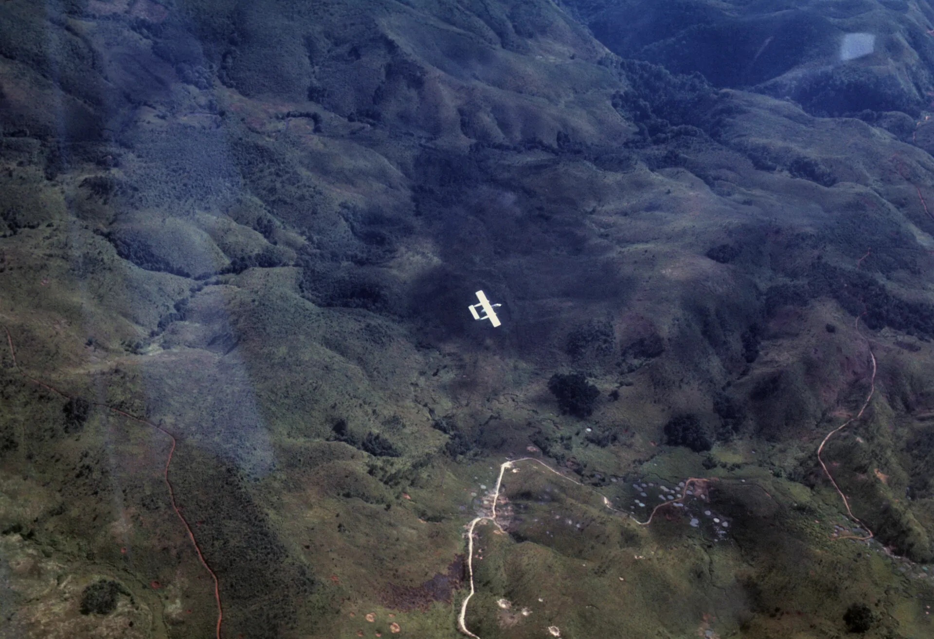 Aerial View of Small Fixed-Wing Aircraft over Mountainous Jungle Terrain, Southeast Asia (Vietnam War Era Slide)