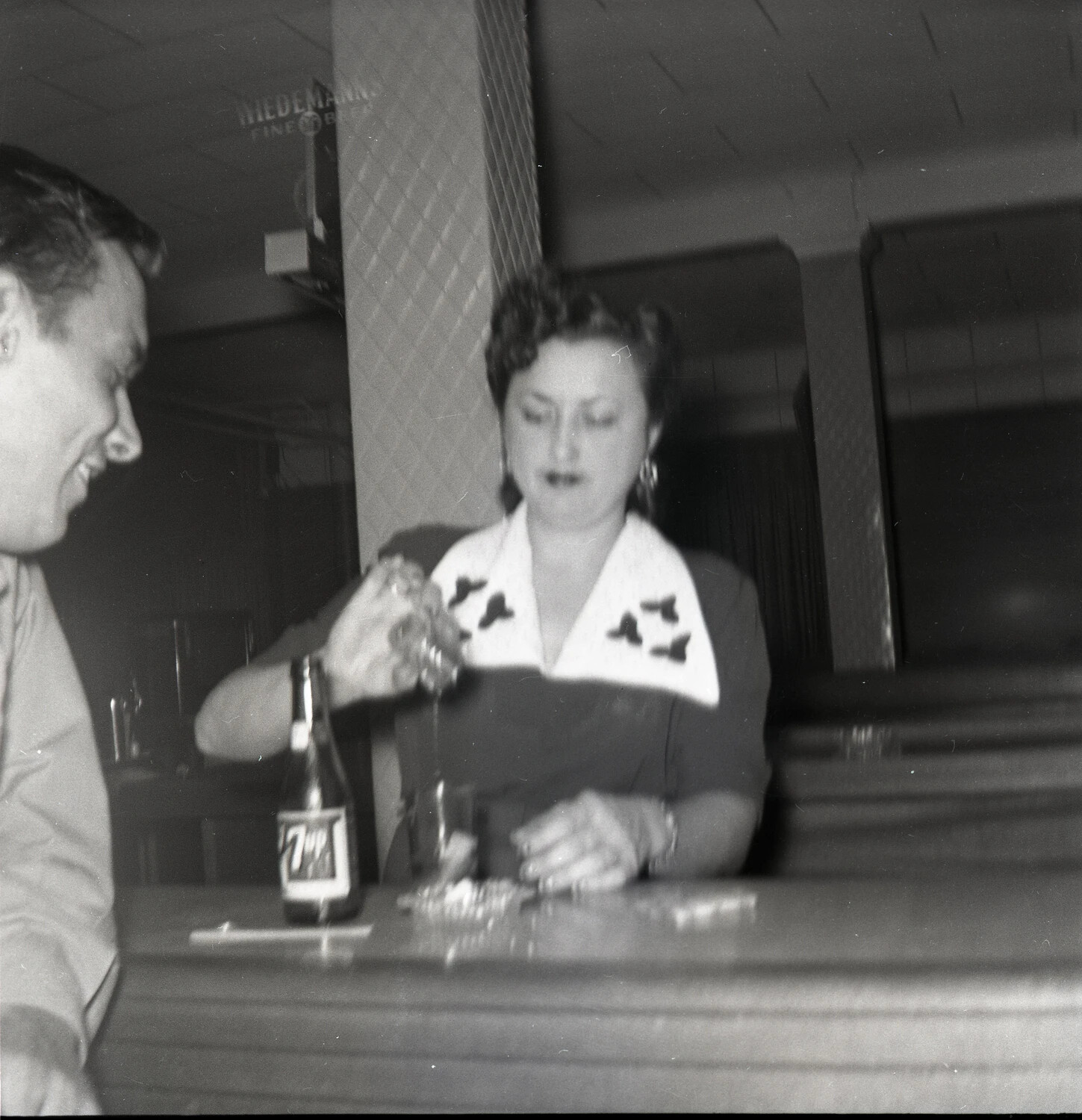 Woman and Man at the Bar with a 7 Up Bottle, Wiedemann's Sign in Background, Early 1950s