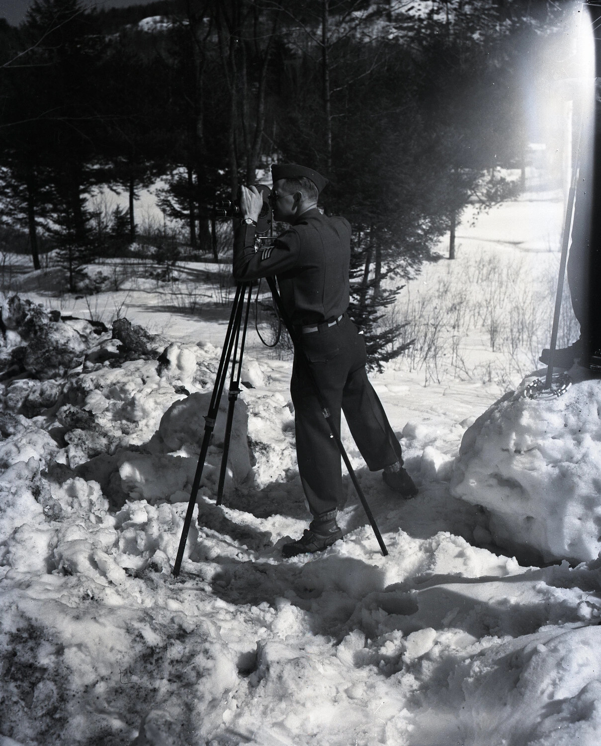 Serviceman Filming with Tripod-Mounted Motion Picture Camera in Snow, WWII Era