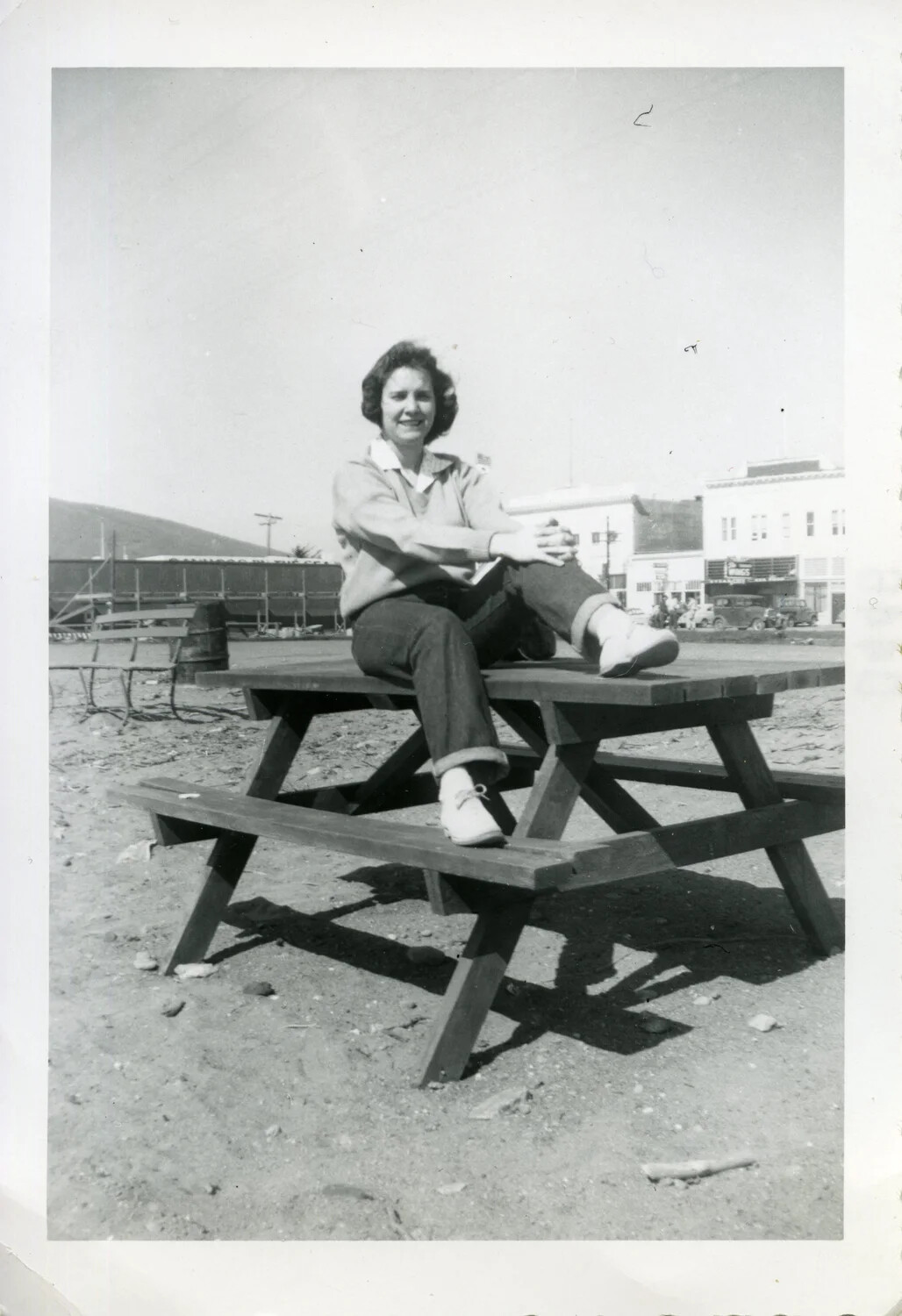 Young Woman Seated on Picnic Table, Small-Town Main Street Background, Korean War Era