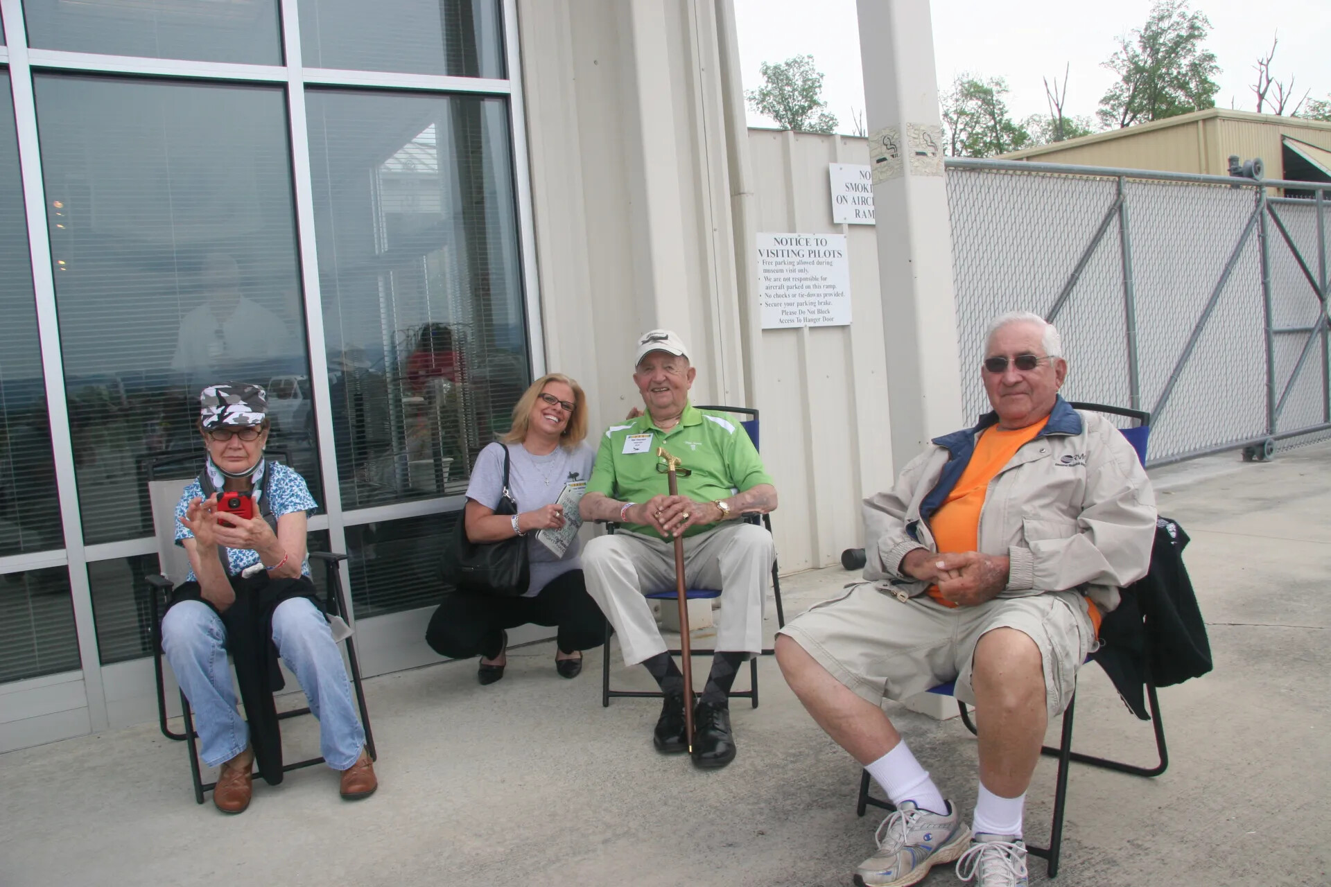 Reunion Attendees Seated Outside Museum Entrance Near Aircraft Ramp