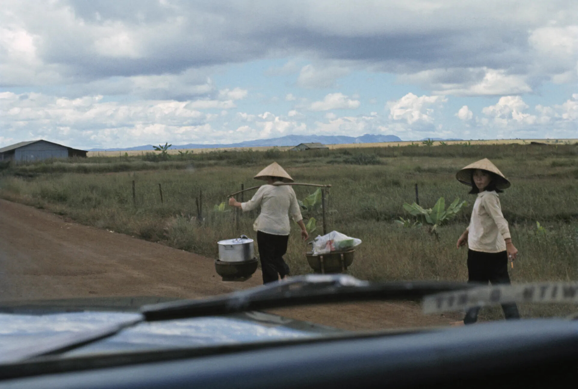 Vietnamese Women With Shoulder Poles Along a Rural Road