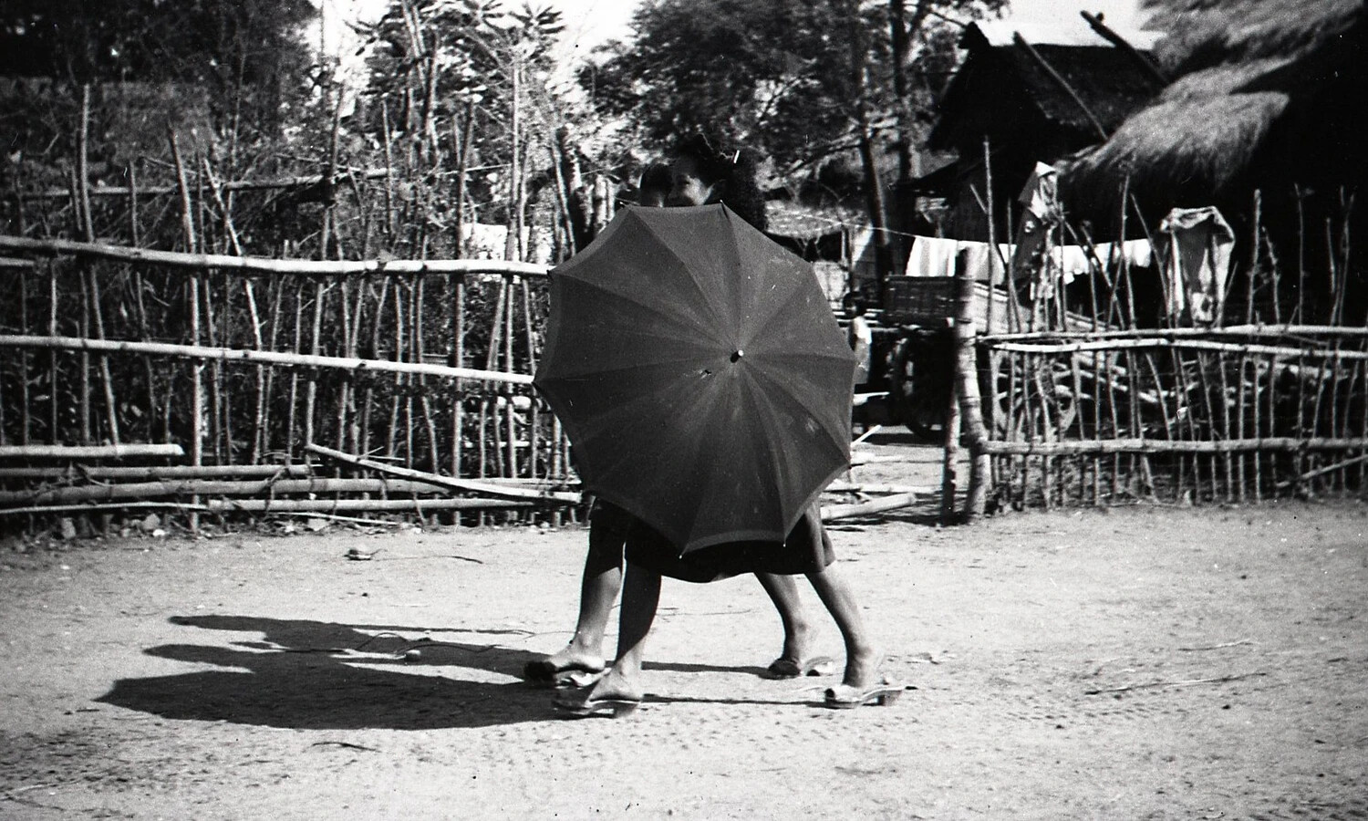 Filipino Women Sharing an Umbrella in a Village Yard, Luzon, WWII Era