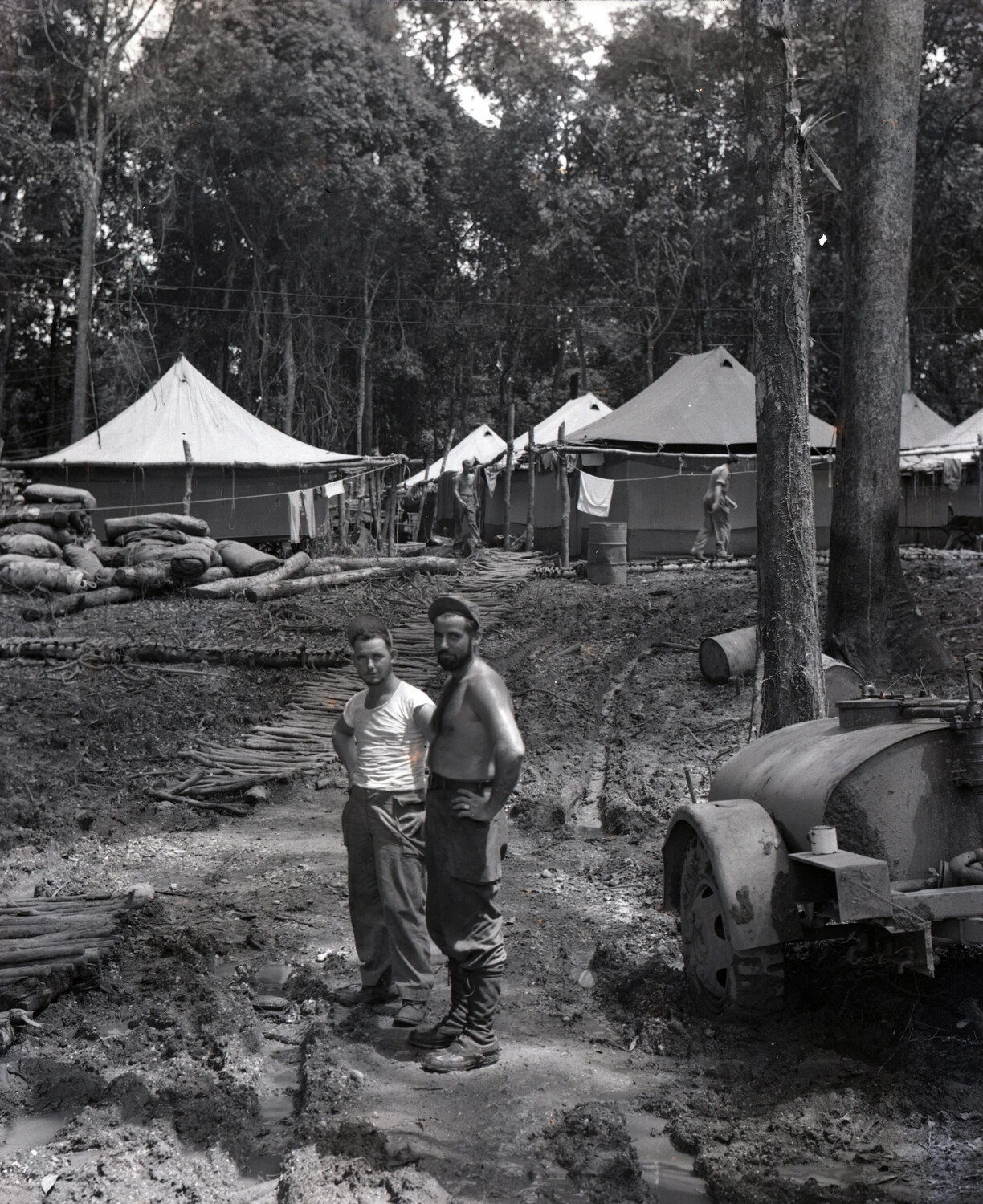 Servicemen in Muddy Jungle Camp with Tent Row and Fuel Trailer, China-Burma-India Theater, WWII (Kotec Collection)